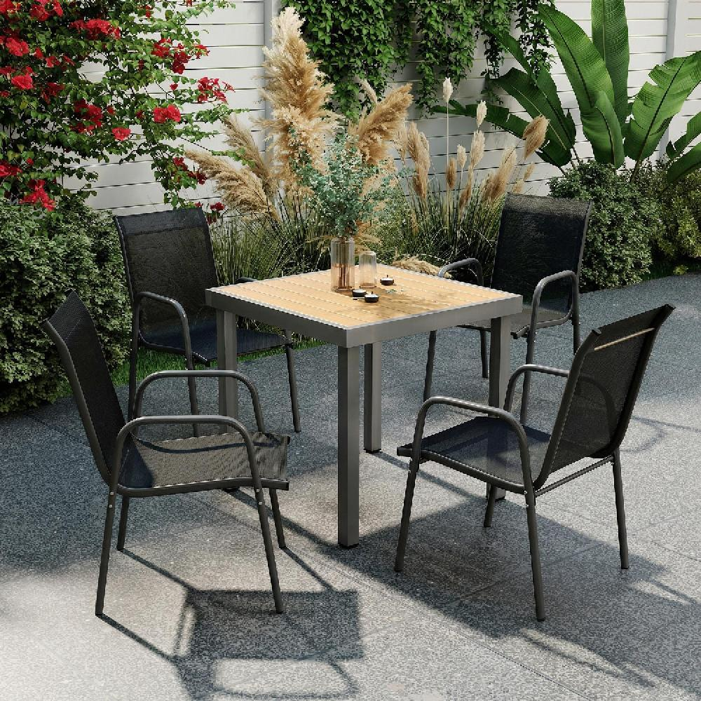 Un tavolo e quattro sedie in un giardino con piante e fiori.