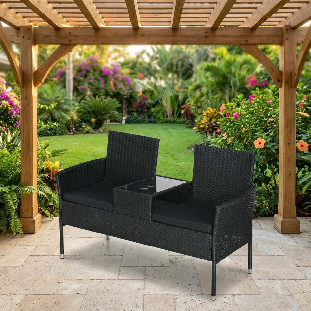 Divanetto doppio in rattan nero con tavolino sotto pergola in legno, vista giardino.