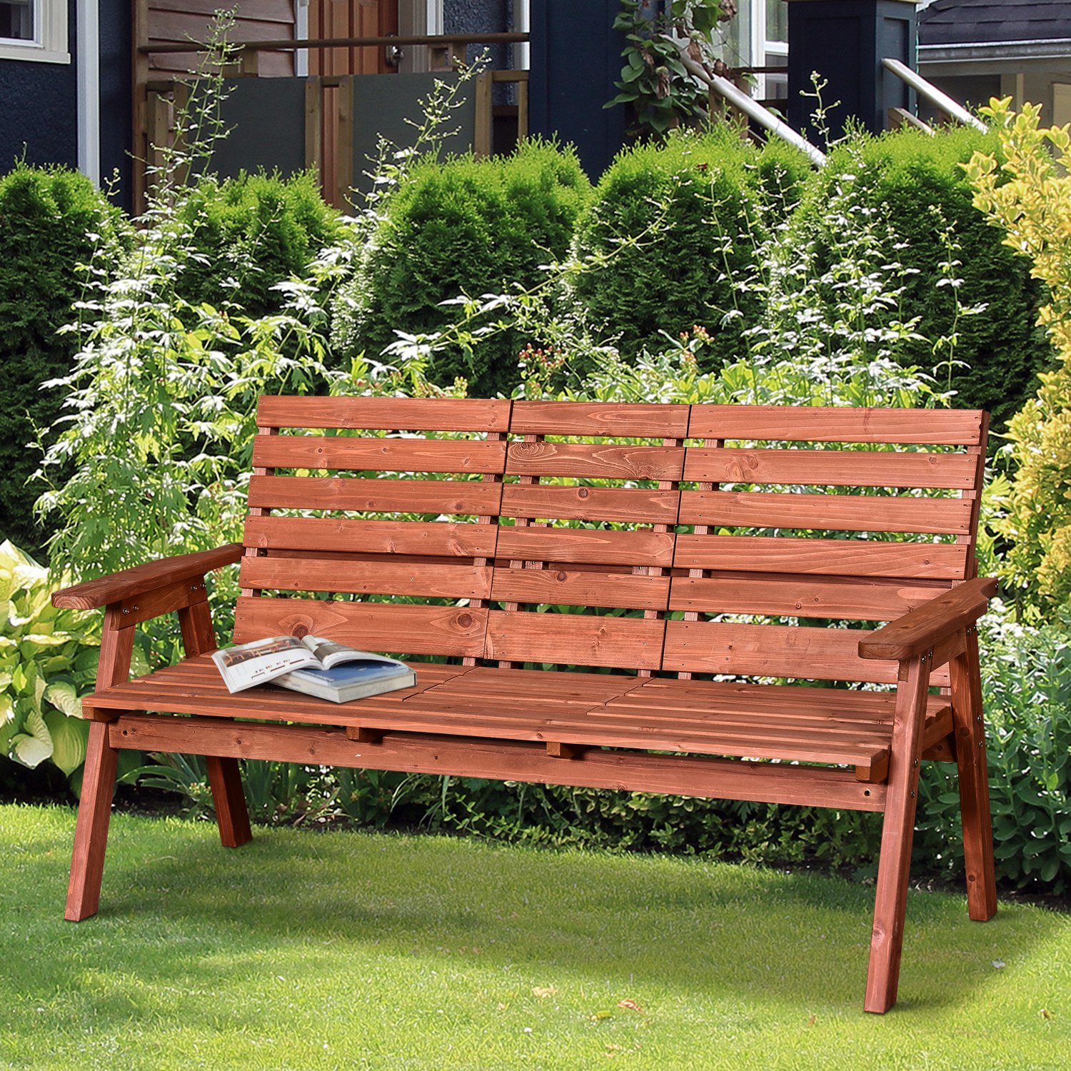 Una panchina di legno marrone con libri è seduta sull'erba verde in un giardino.