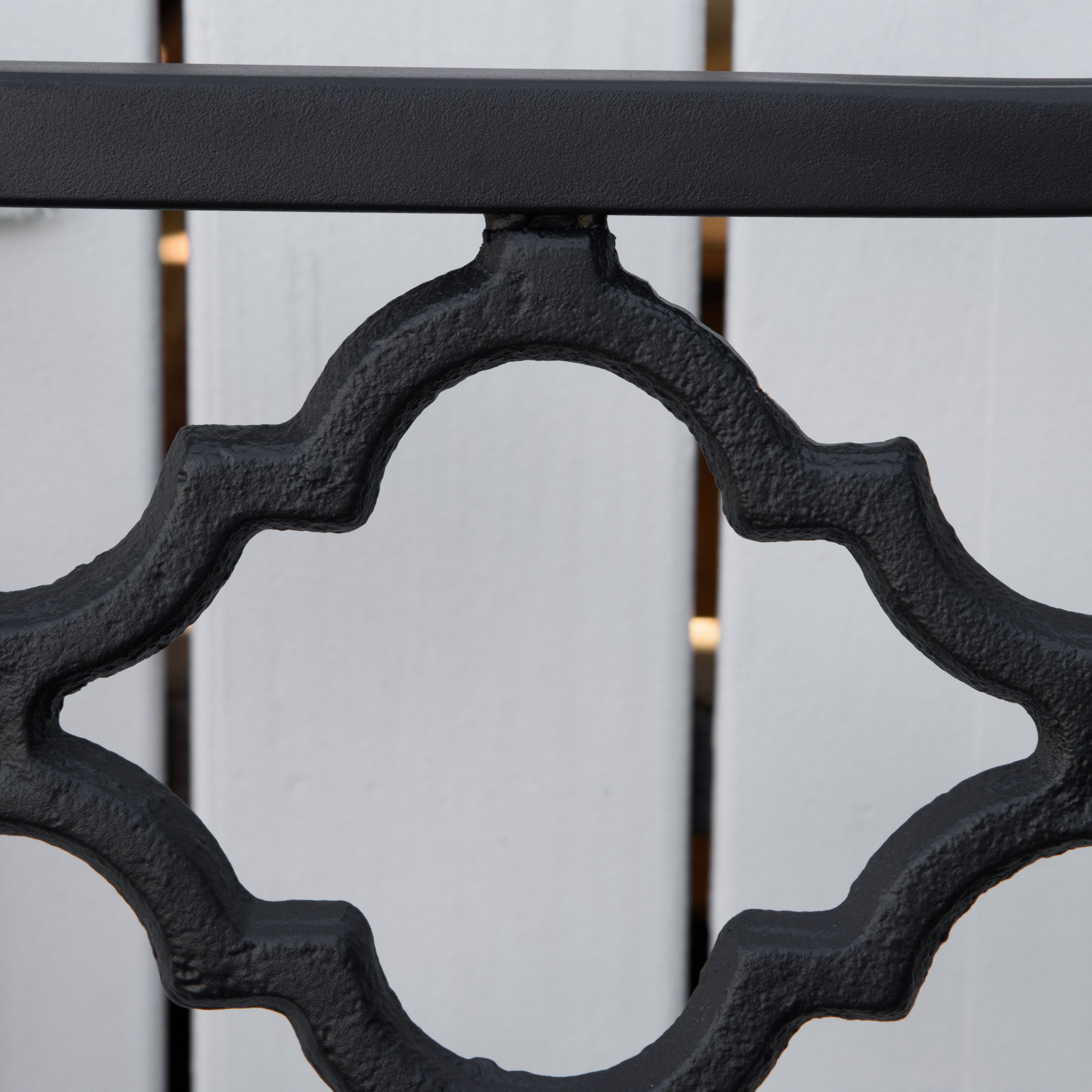 Una ringhiera in metallo nero con motivo geometrico su sfondo bianco.