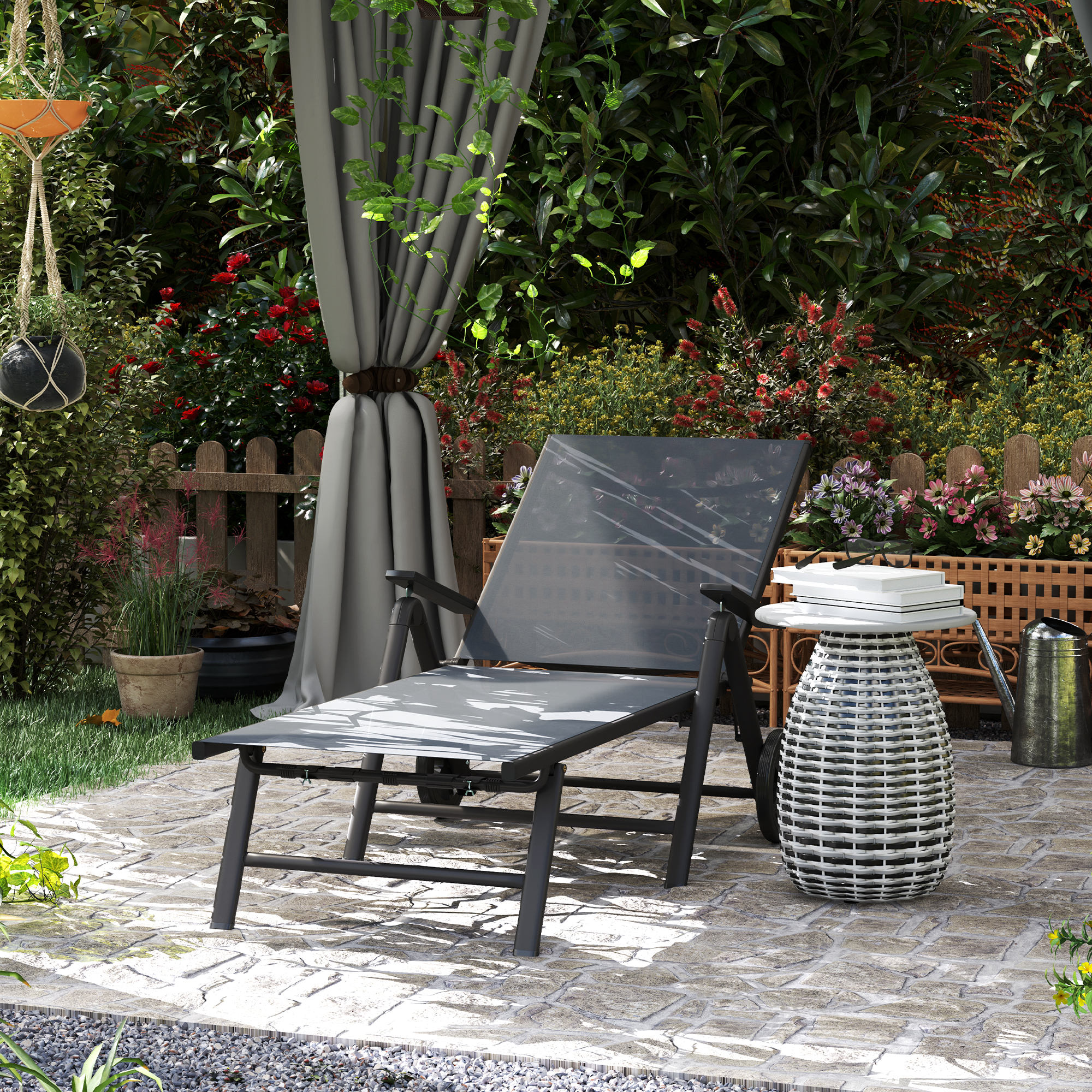 Arredamento da giardino con sdraio, tavolino con libri, annaffiatoio e piante.