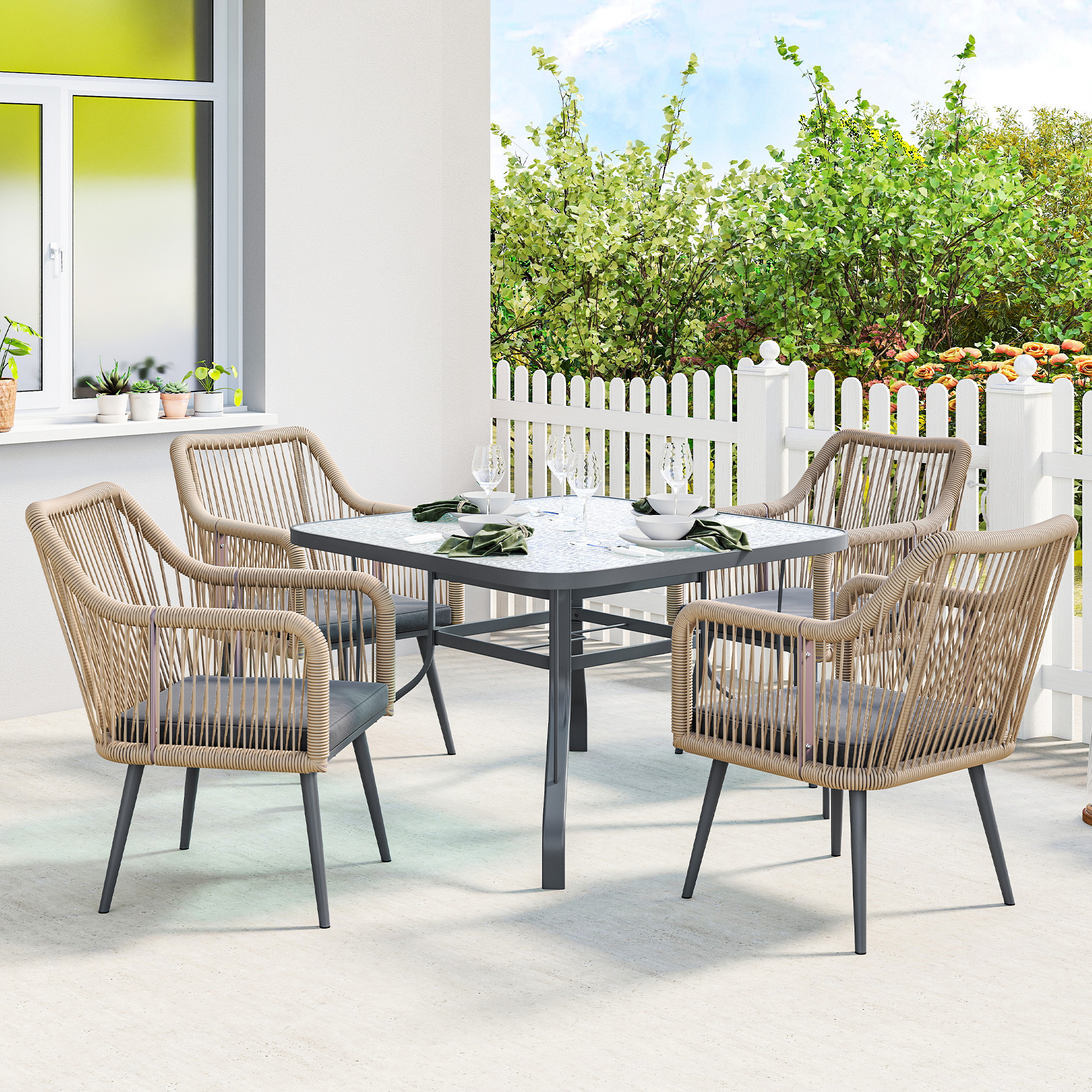 Un tavolo da pranzo con quattro sedie in rattan con cuscini grigi si trova su un patio.