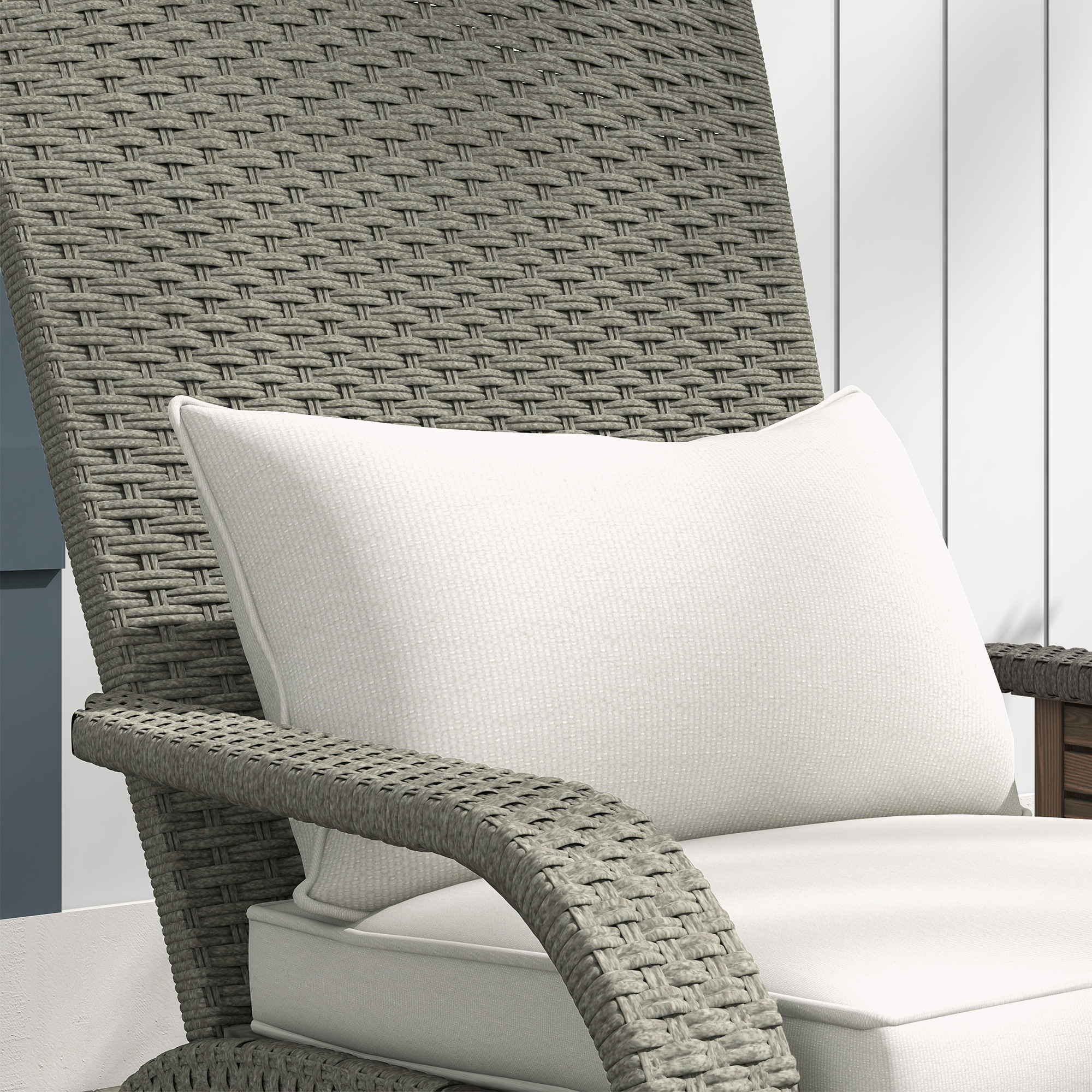 Sedia in rattan grigio con cuscino e seduta bianchi, all'aperto.