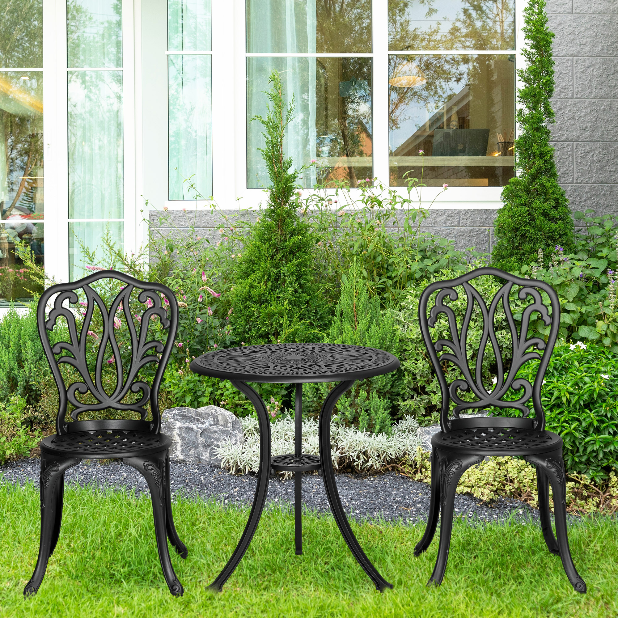 Un tavolino da bistrot nero e due sedie sono in un giardino.