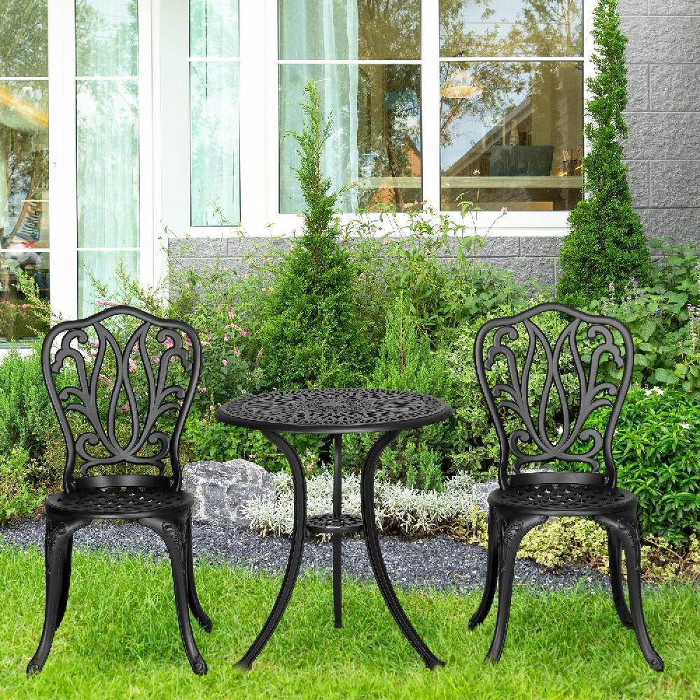 Un set da tavolo in ghisa nera con due sedie e un tavolo rotondo in un giardino.