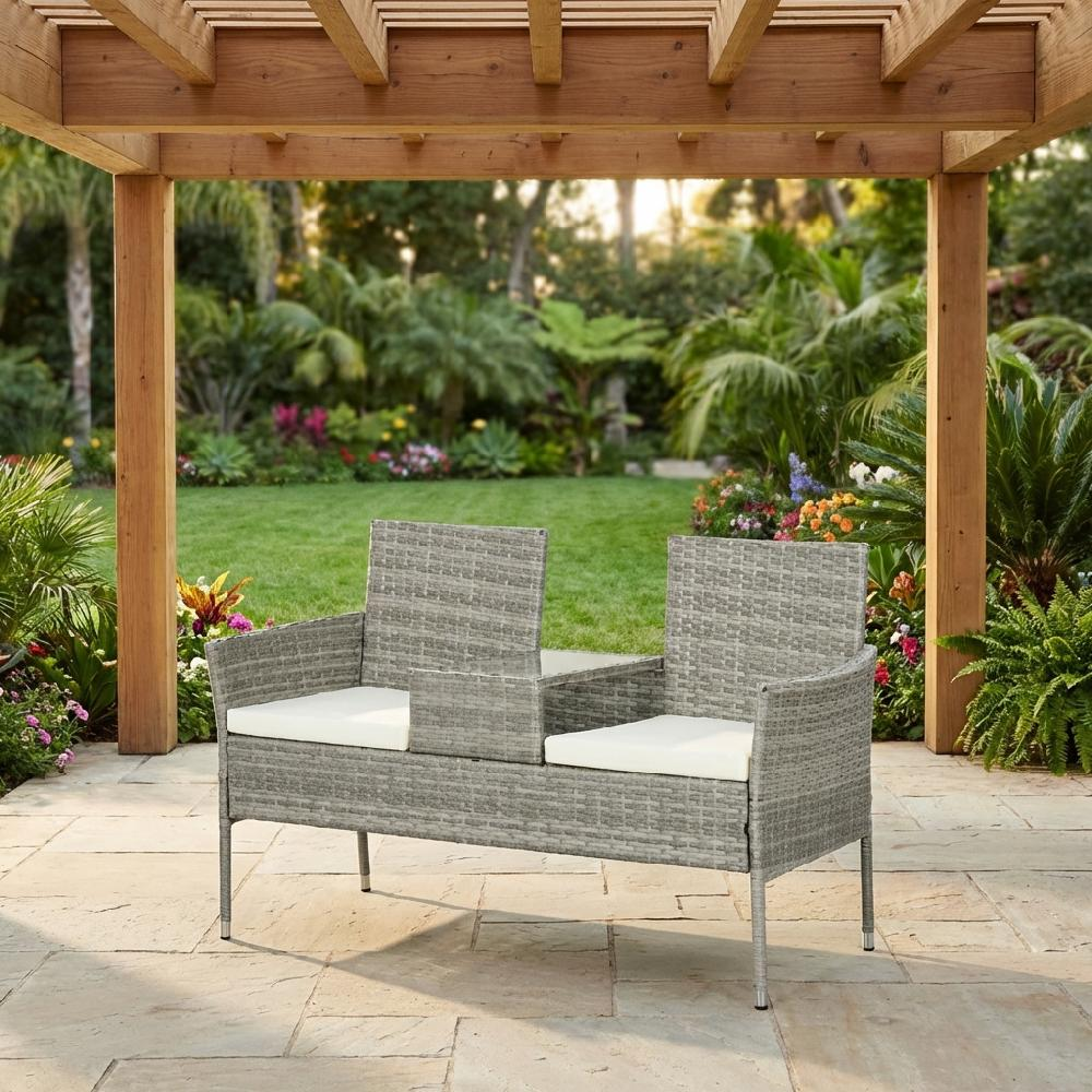 Divanetto grigio sotto pergola in legno con vista su giardino lussureggiante.
