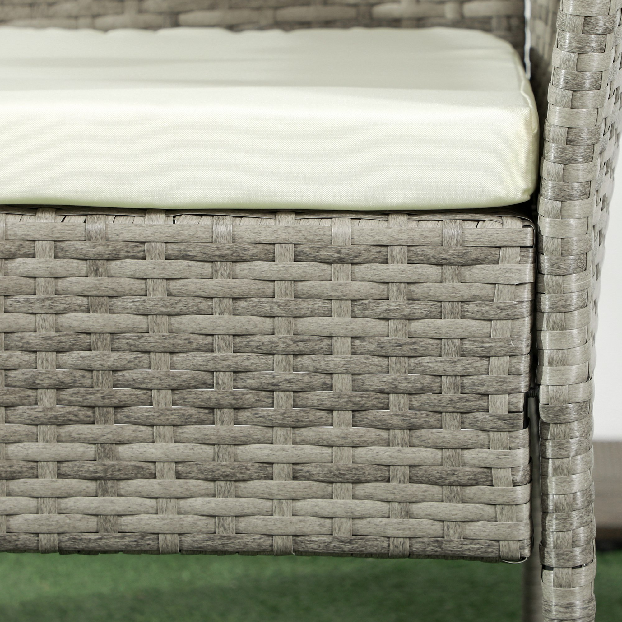 Sedia in rattan grigio con cuscino color crema su erba sintetica verde.