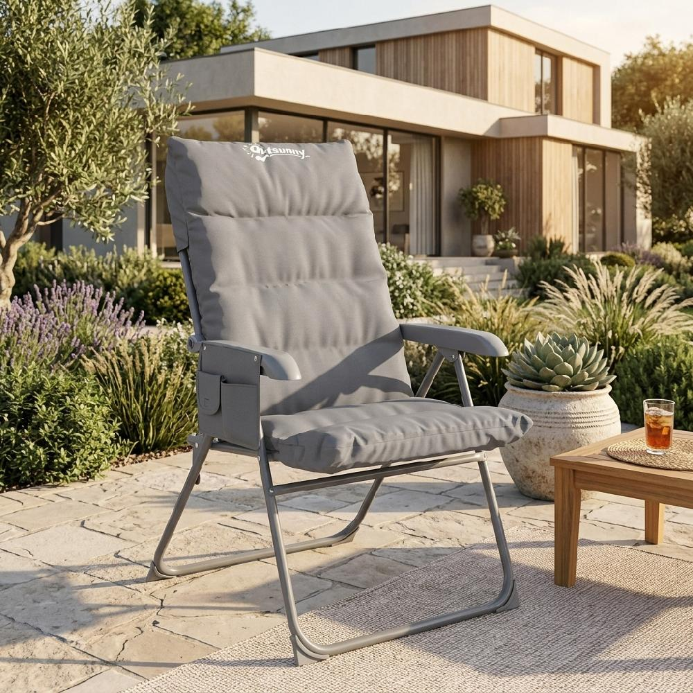Una sedia pieghevole grigia con cuscini si trova su un patio vicino a una casa moderna.