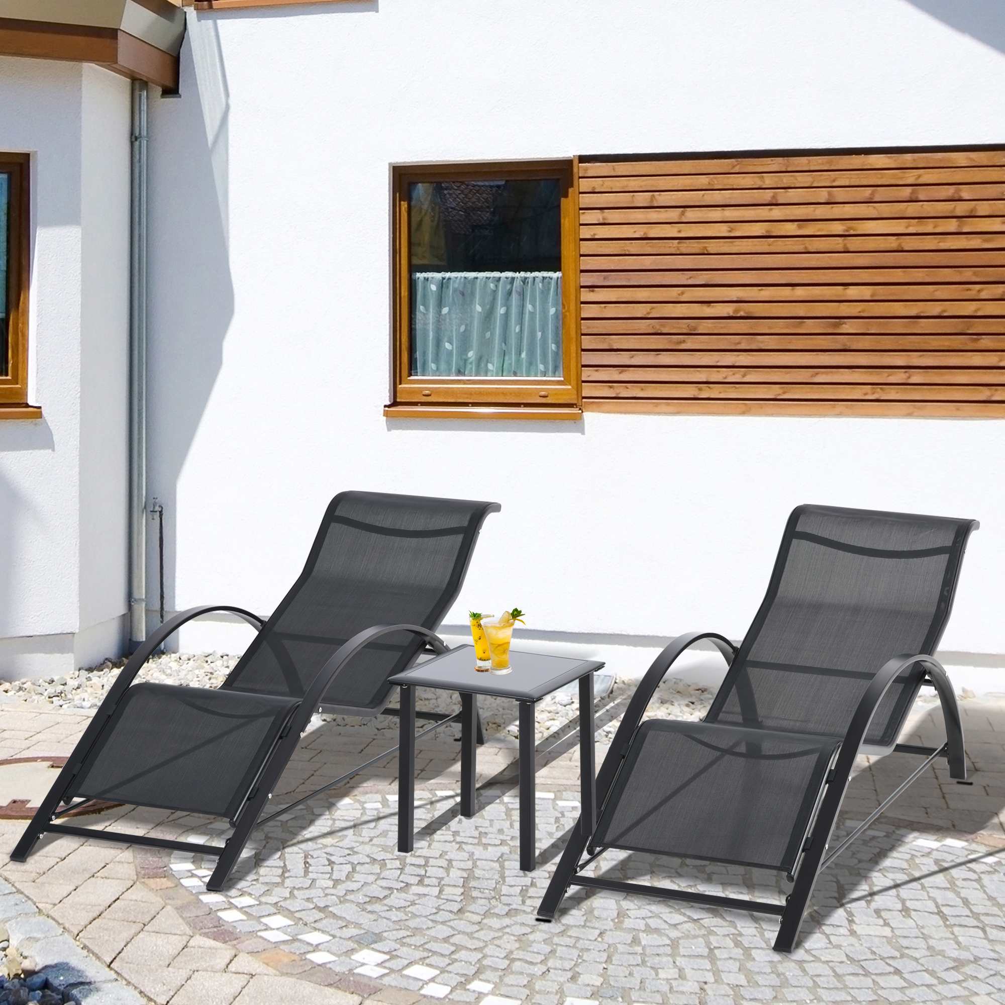 Due sdraio scure e un tavolino con bevande su un patio di pietra.