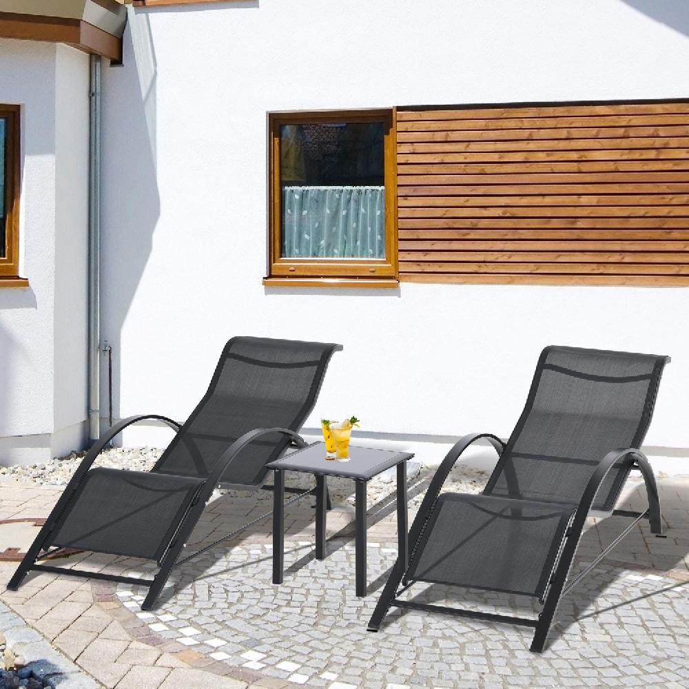Due lettini scuri e un tavolino con bevande su un patio pavimentato.