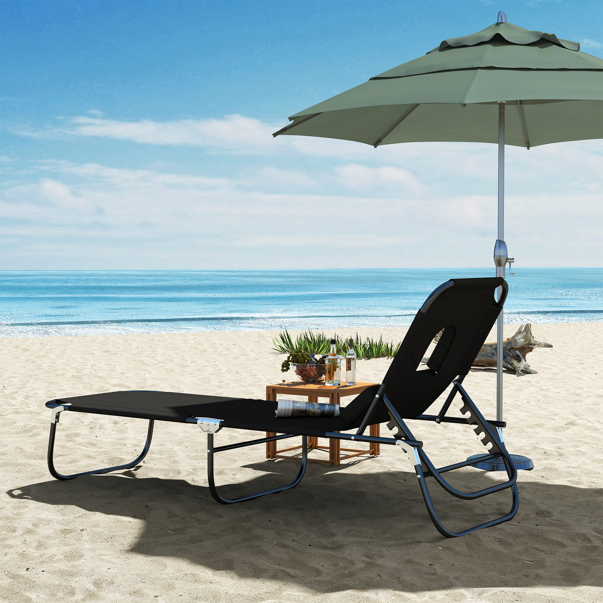 Una sdraio e un tavolo neri con frutta e bevande su una spiaggia.