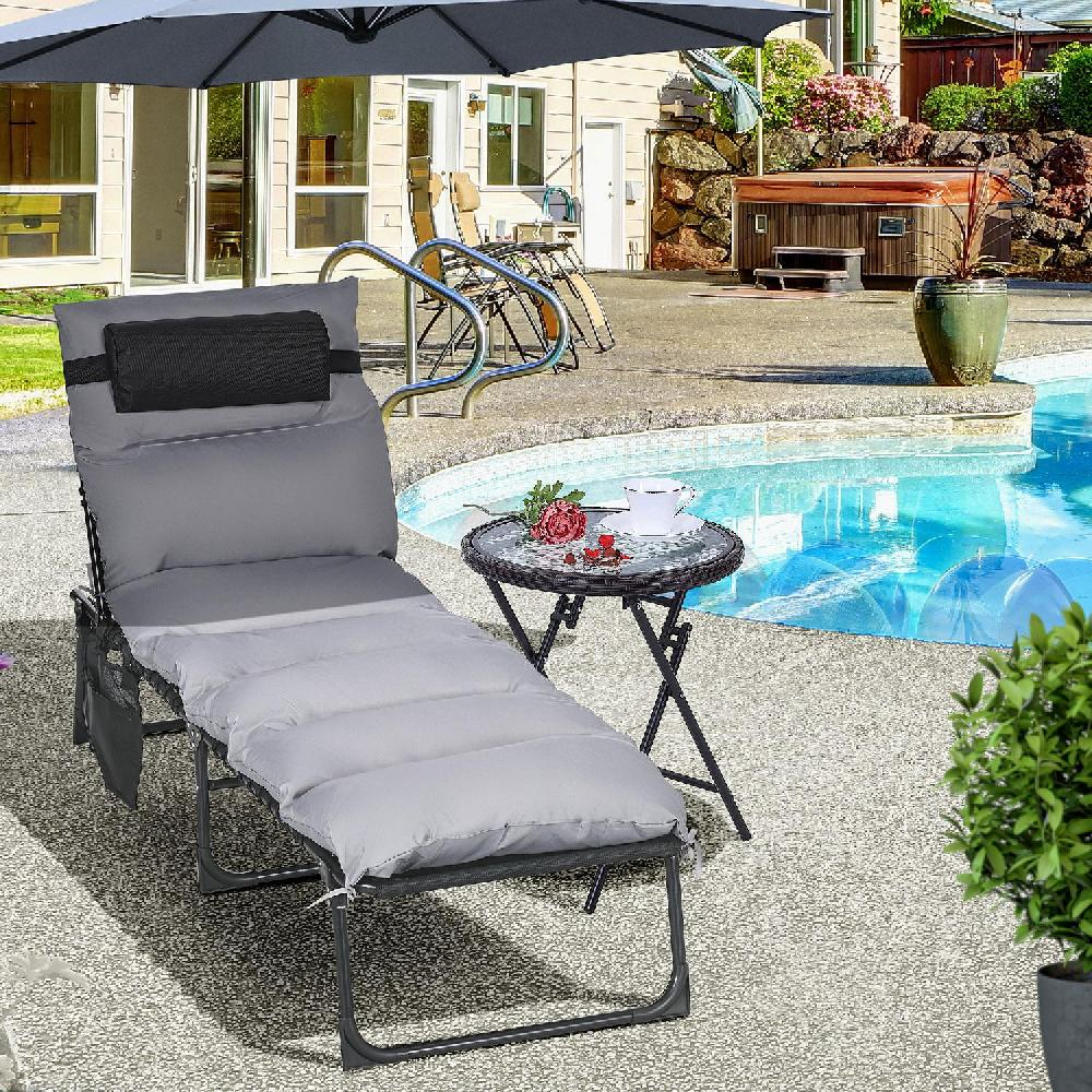 Sdraio grigio vicino a una piscina con tavolino, tazza e fiore.