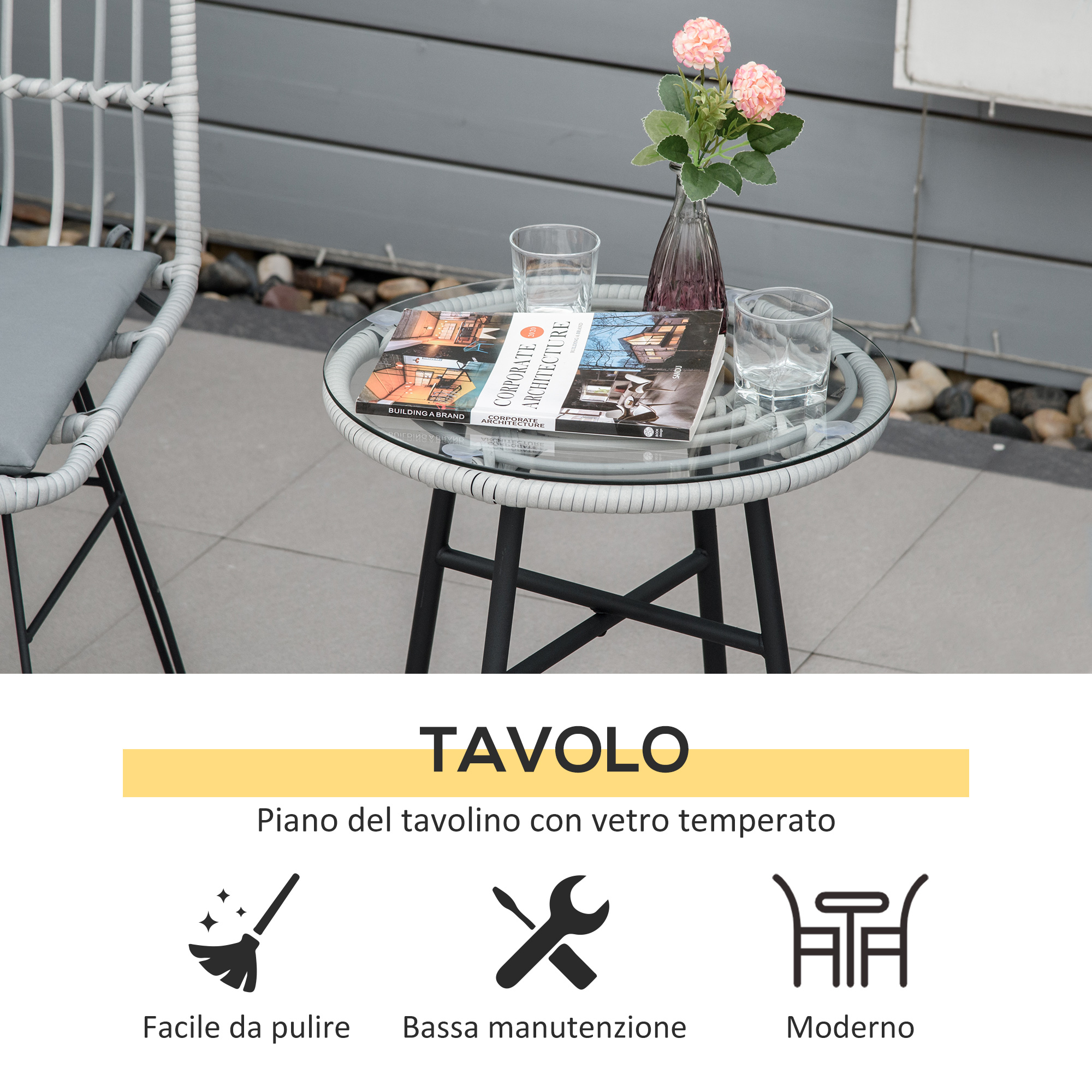 Una sedia in rattan bianca accanto a un tavolino di vetro con libri, bicchieri e fiori.