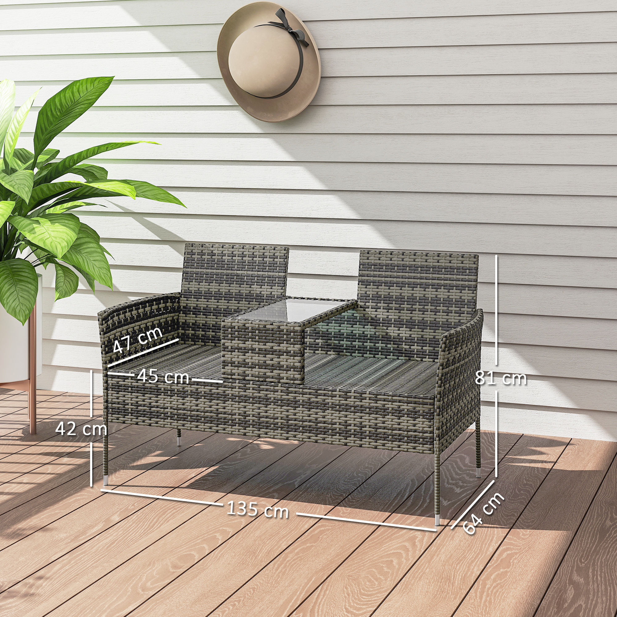 Divano in rattan a due posti con tavolino in vetro su deck di legno, accanto a una pianta.