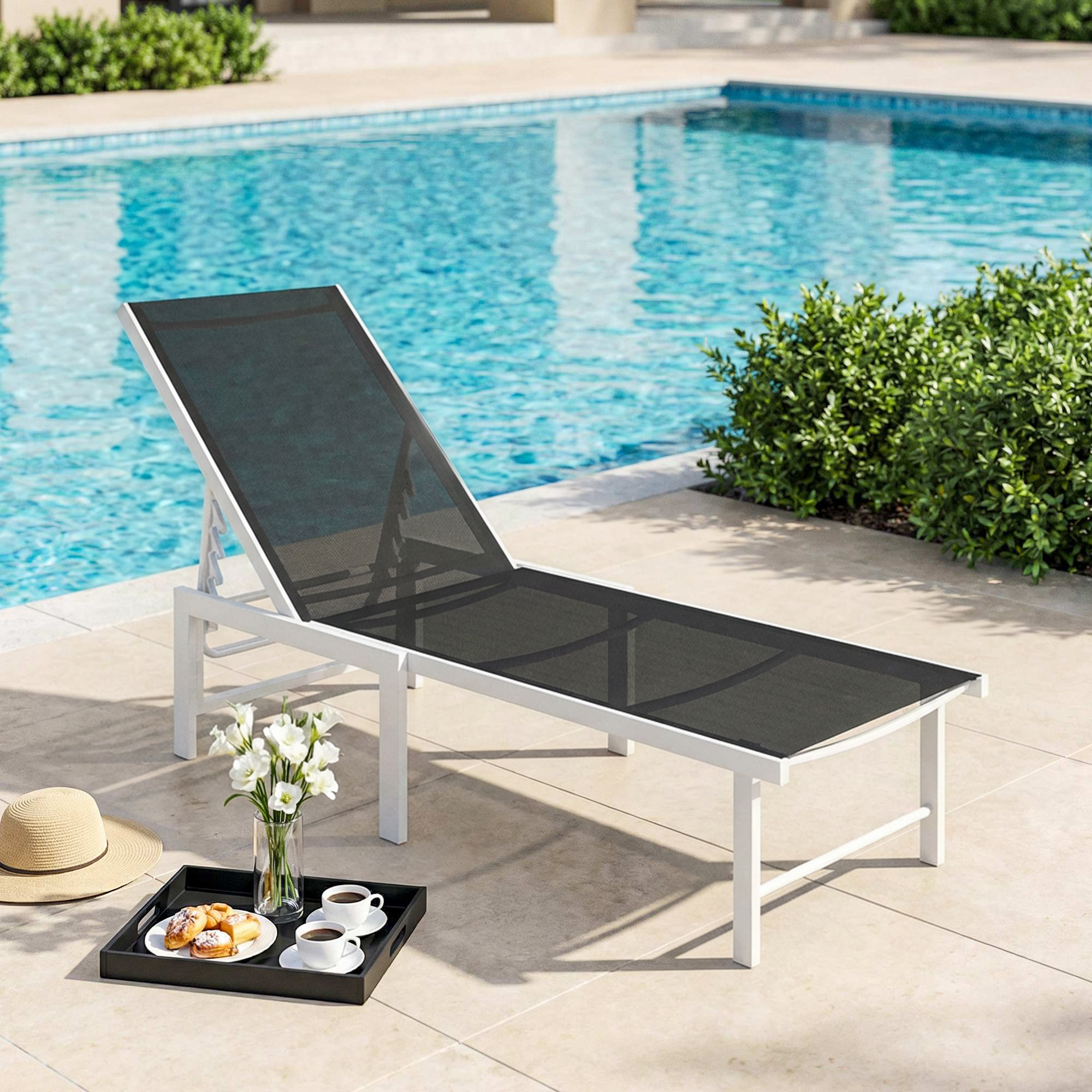 Un lettino bianco con rete nera vicino a una piscina, con un vassoio di pasticcini e caffè nelle vicinanze.