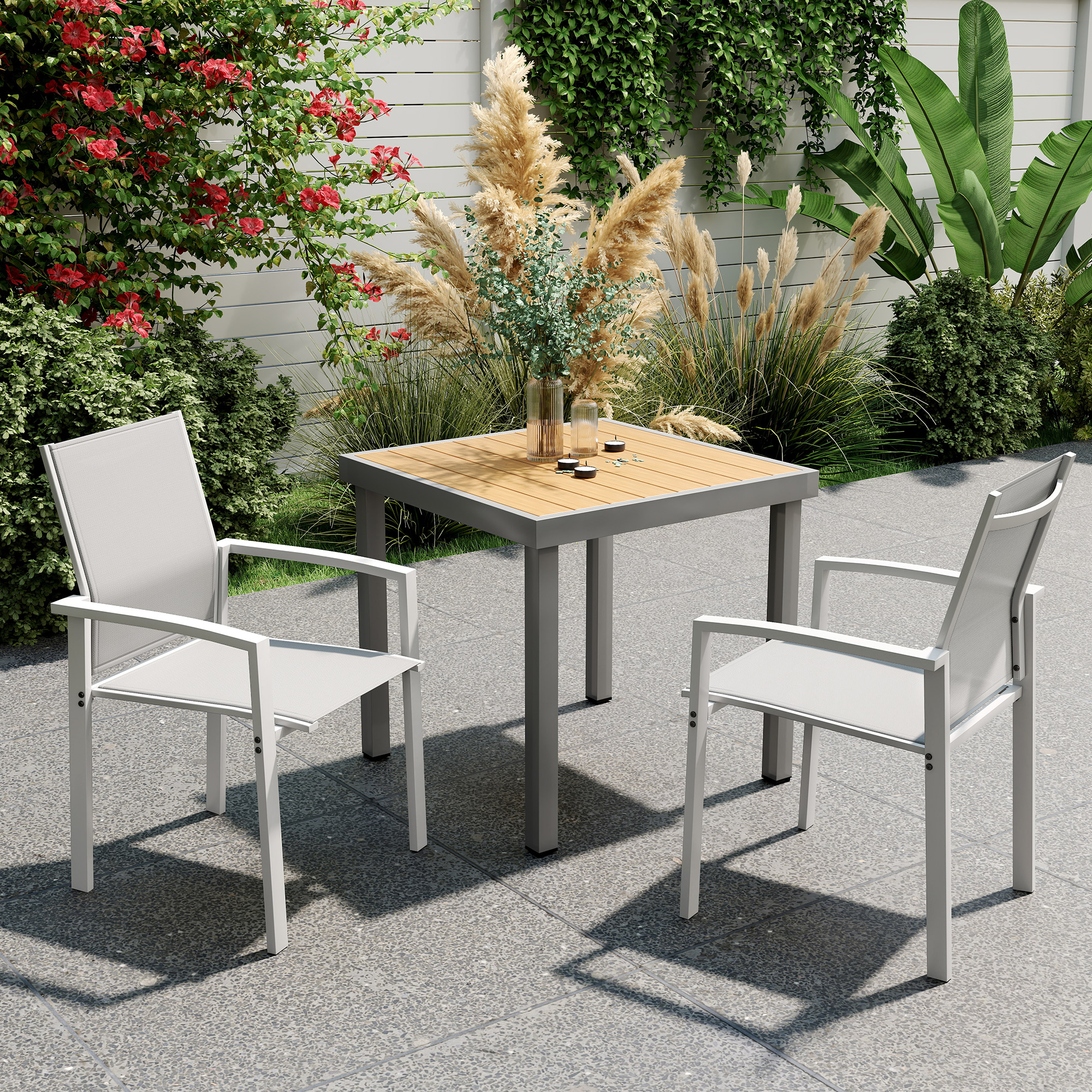 Patio esterno con tavolo quadrato e due sedie bianche, circondato dal verde.