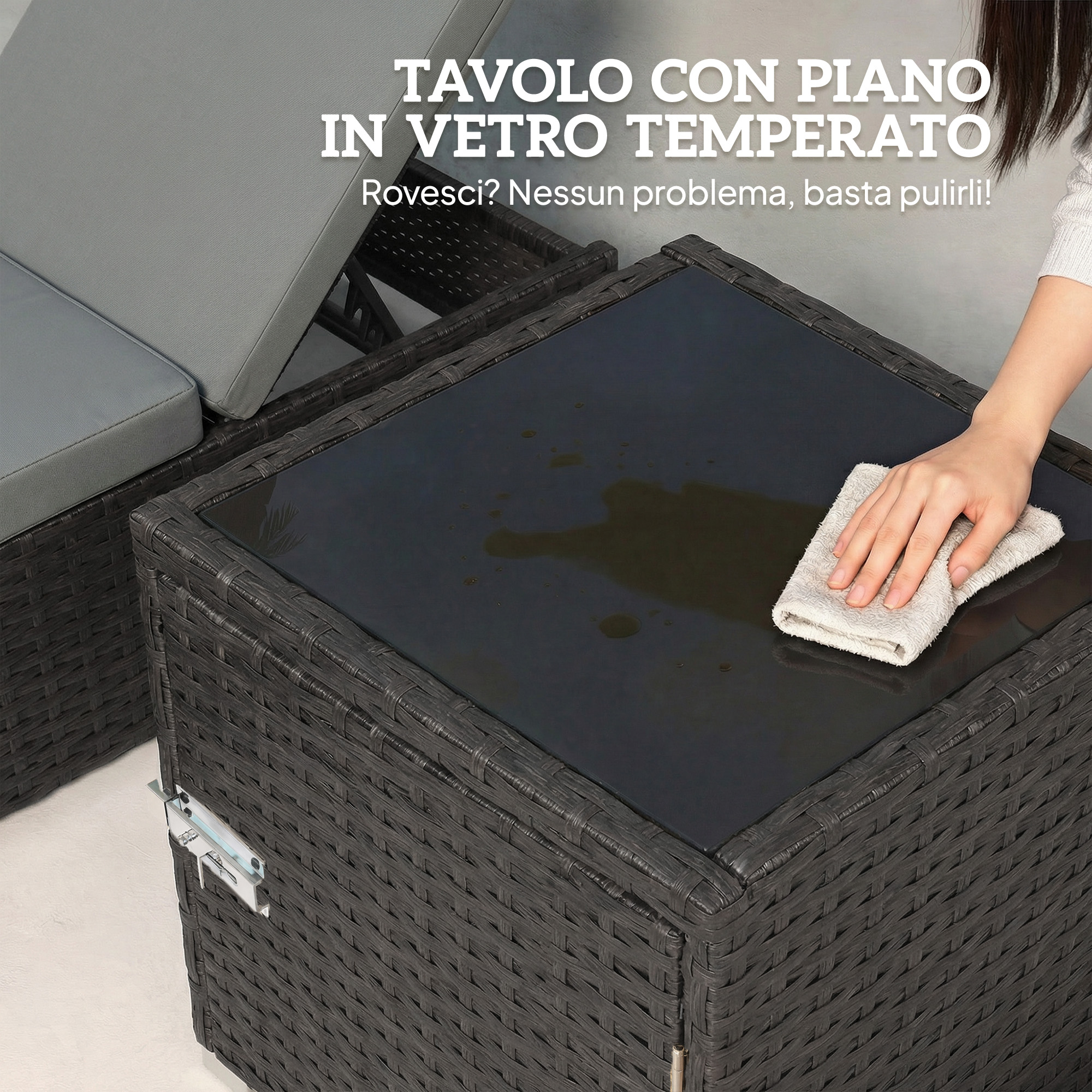 Una mano pulisce un tavolo con piano in vetro scuro su base in rattan.