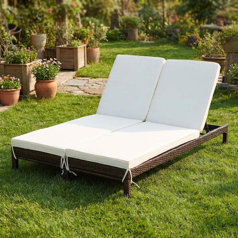 Una chaise longue doppia marrone con cuscini bianchi su prato verde circondato da piante.