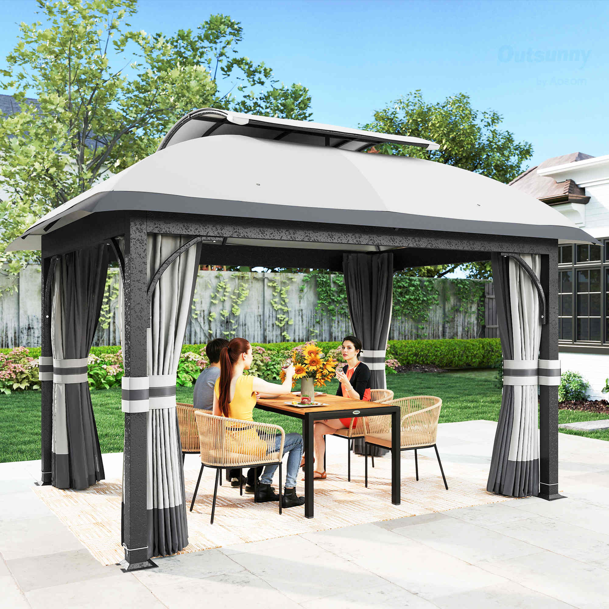 Tre persone siedono a un tavolo sotto un gazebo in un giardino.