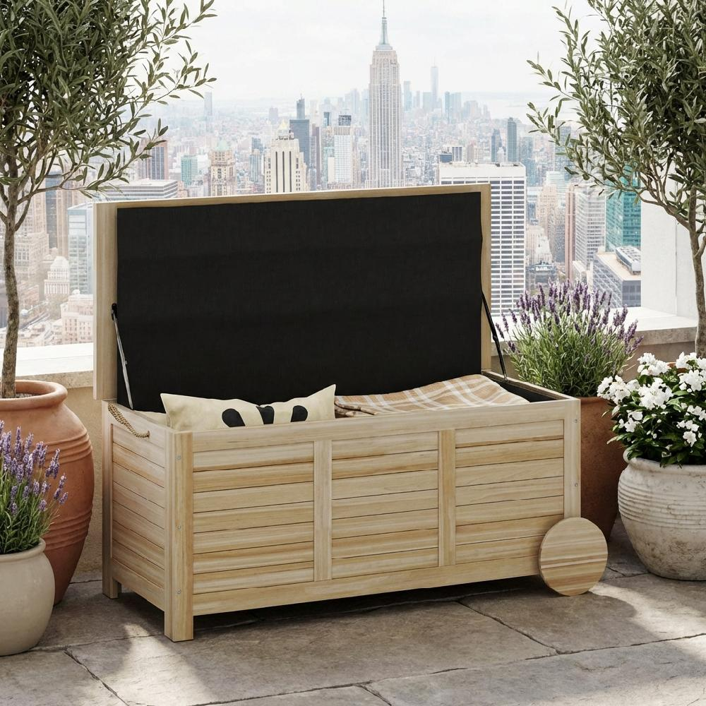 Baúle in legno con coperchio aperto su balcone con vista sulla città, cuscino.