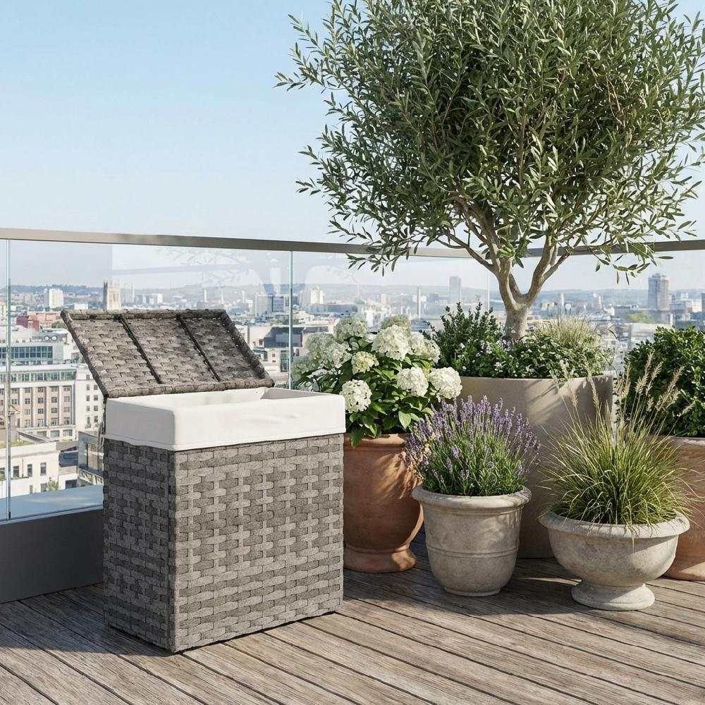 Cesto contenitore grigio intrecciato con coperchio aperto su terrazza in legno con piante.