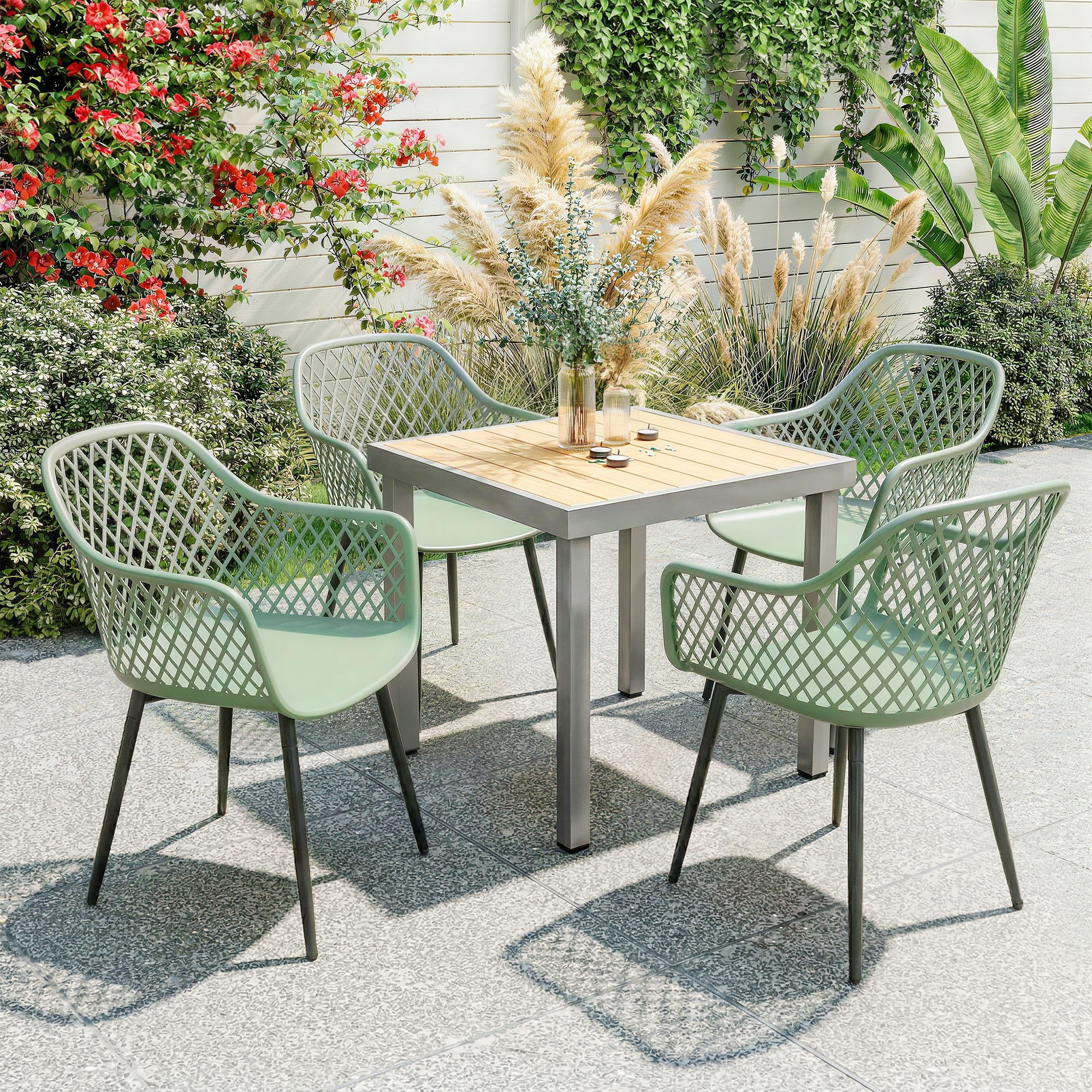 Un tavolo da giardino con quattro sedie verdi e erba secca sullo sfondo.