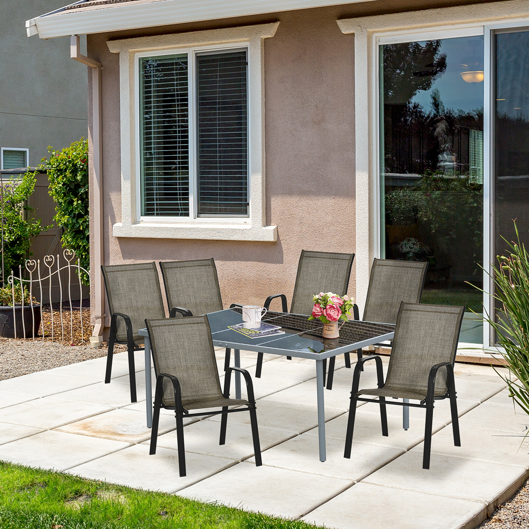 Un set da pranzo da patio con sei sedie su un patio pavimentato fuori da una casa.