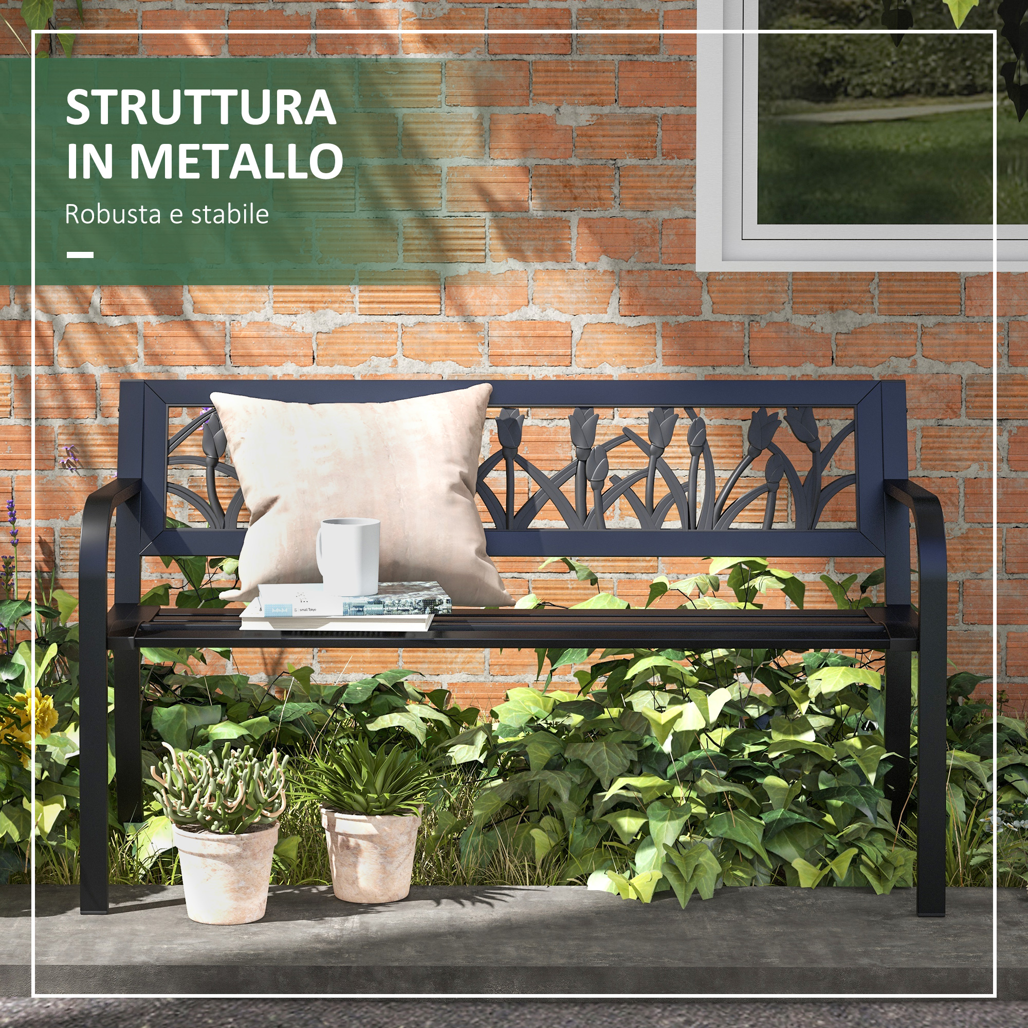 Panca in metallo nera con schienale floreale, cuscino e libri contro muro di mattoni.