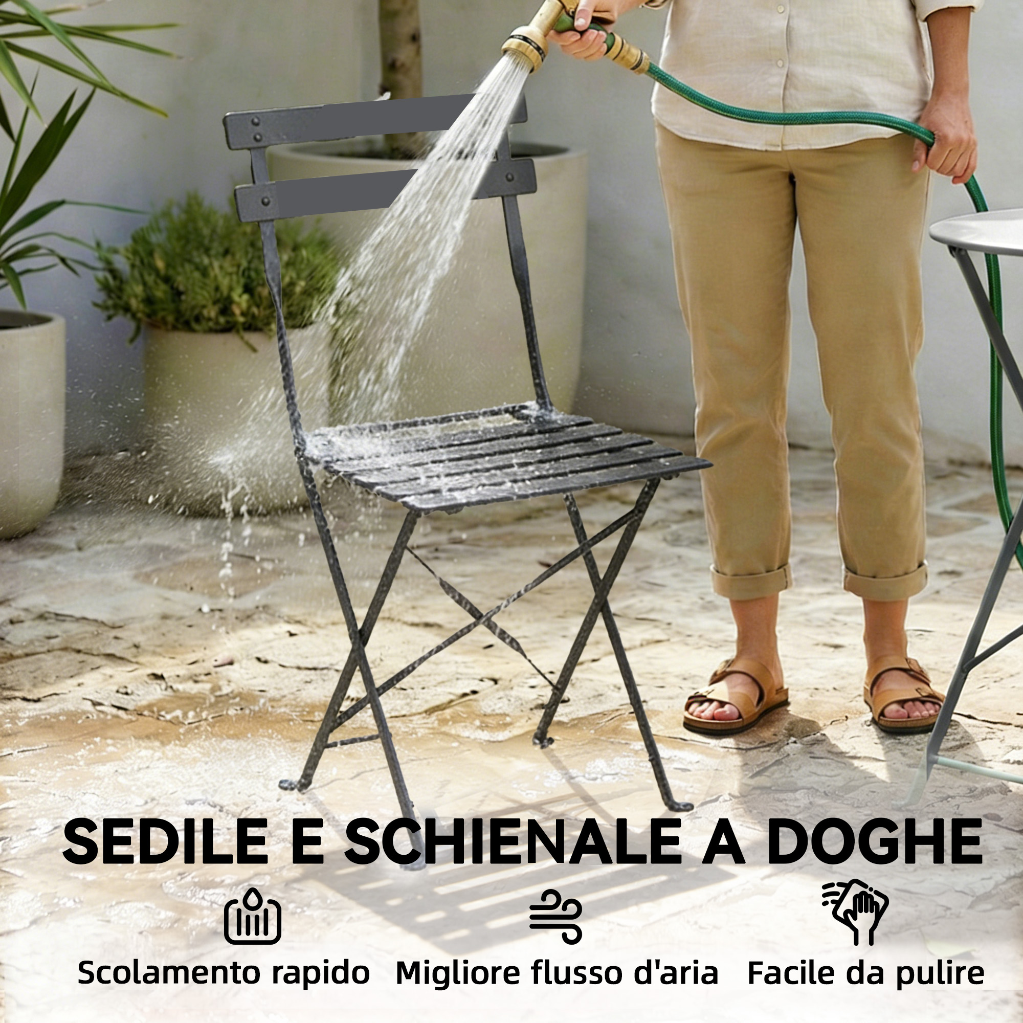 Una persona spruzza una sedia in metallo scuro con un tubo da giardino.