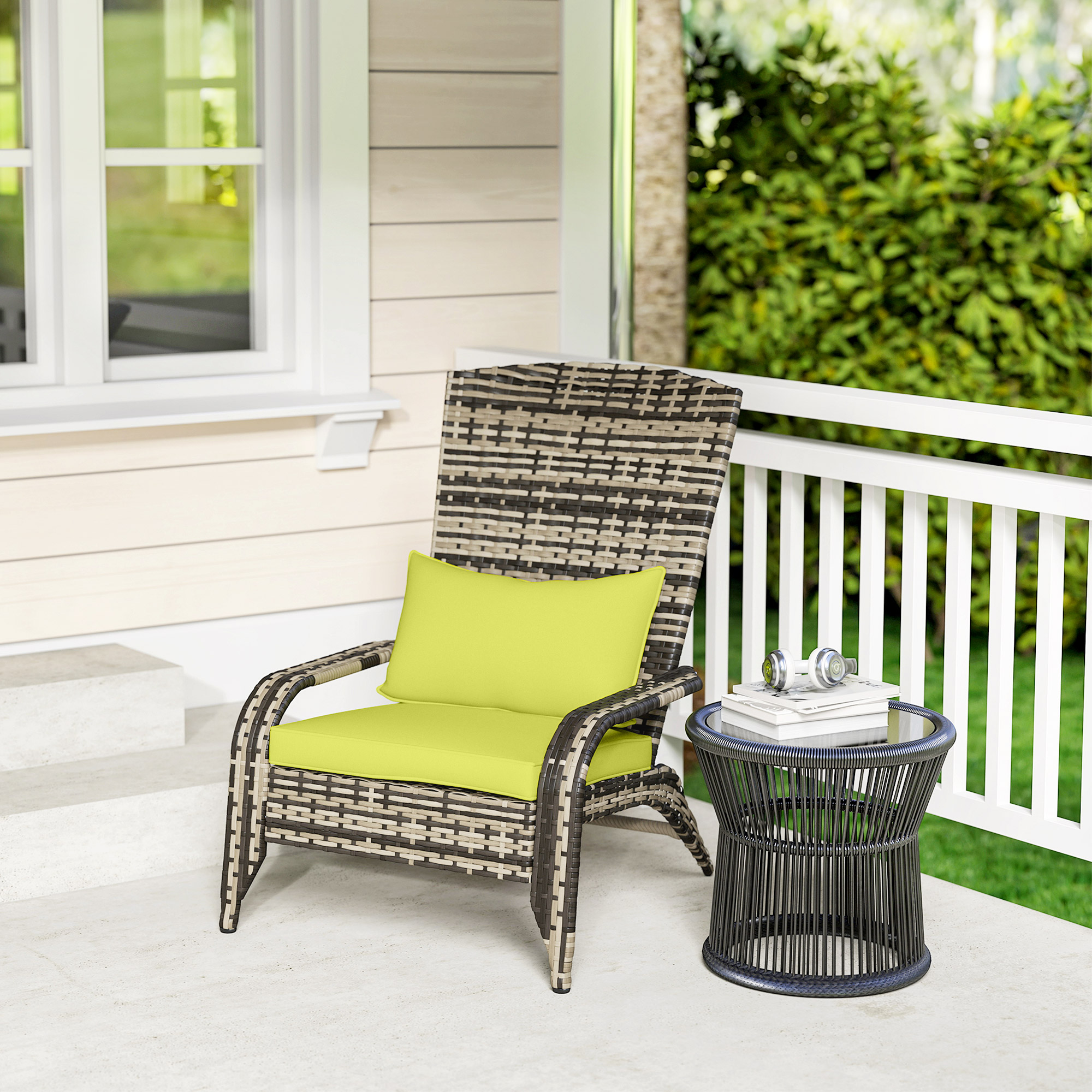 Una poltrona in rattan con cuscino verde lime su un portico vicino a un tavolino.