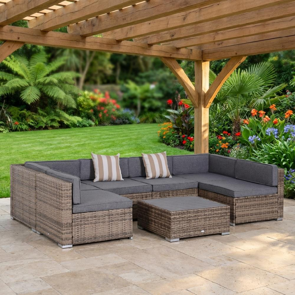 Set da salotto in rattan grigio con cuscini sotto un pergolato in legno.