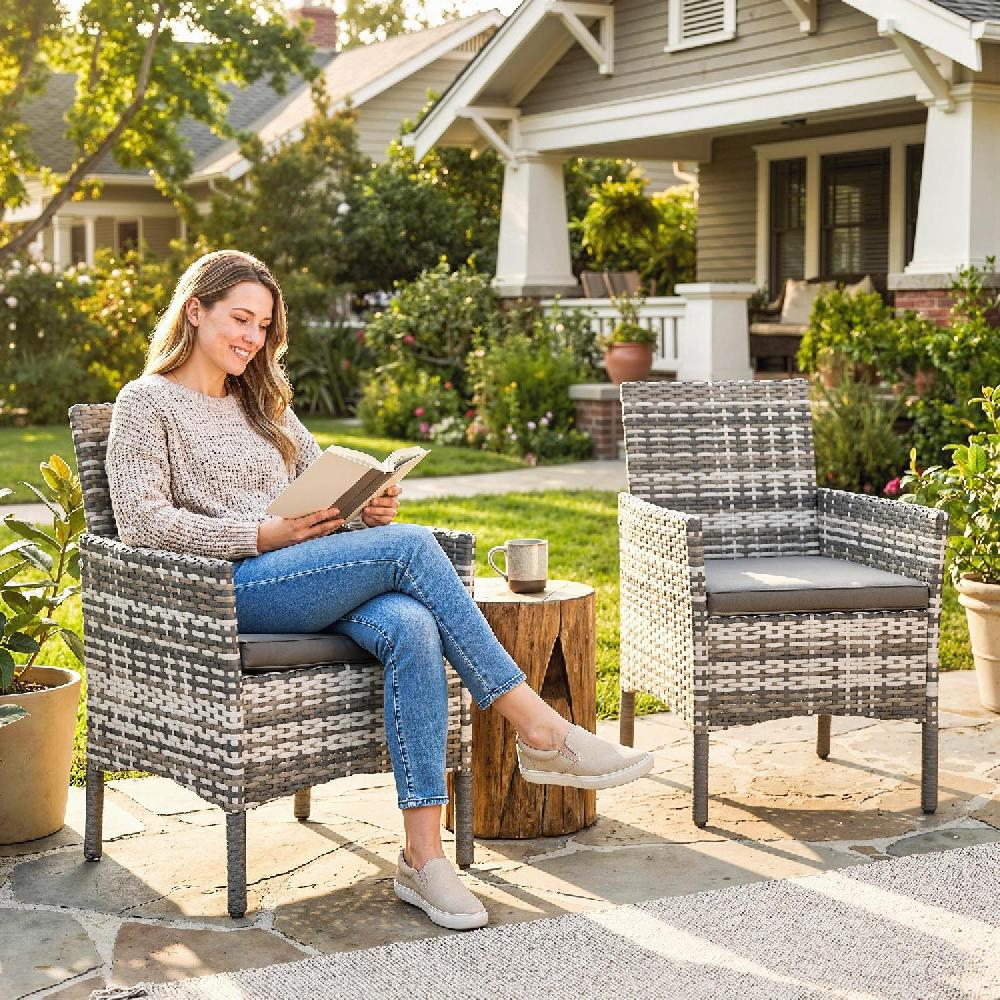 Una donna legge un libro su una sedia in giardino davanti a una casa.