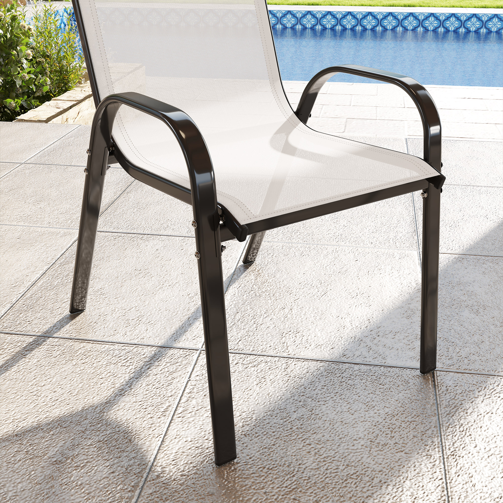 Una sedia bianca in rete con gambe nere su un patio piastrellato vicino a una piscina.