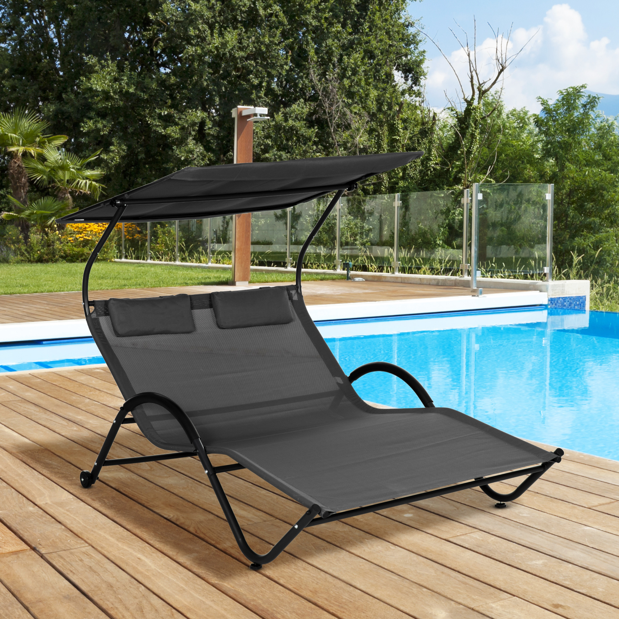 Lettino grigio con tettuccio vicino a una piscina blu su una terrazza in legno.