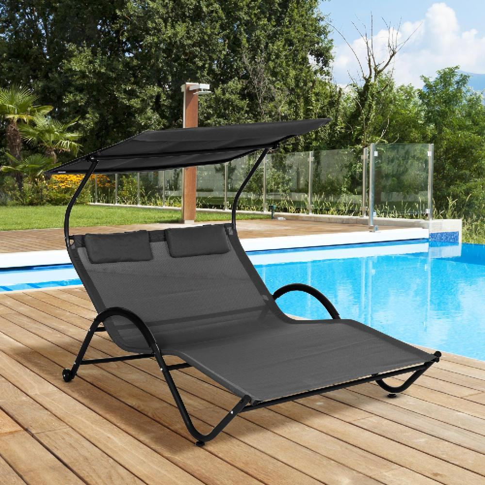 Una sdraio doppia grigia con baldacchino nero siede su un ponte di legno accanto a una piscina.