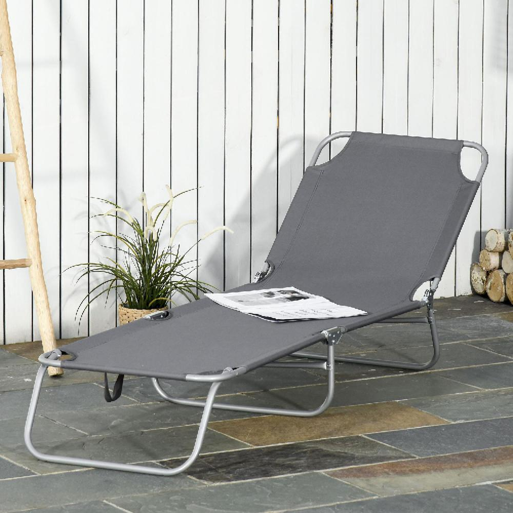 Lettino grigio con giornale su patio in pietra.