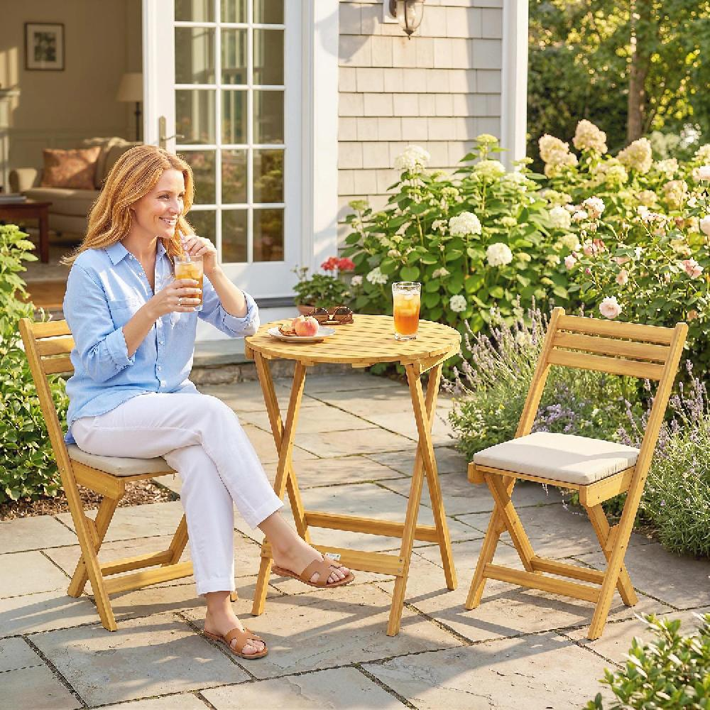 Donna beve tè freddo su patio con tavolo, sedie e fiori in legno.