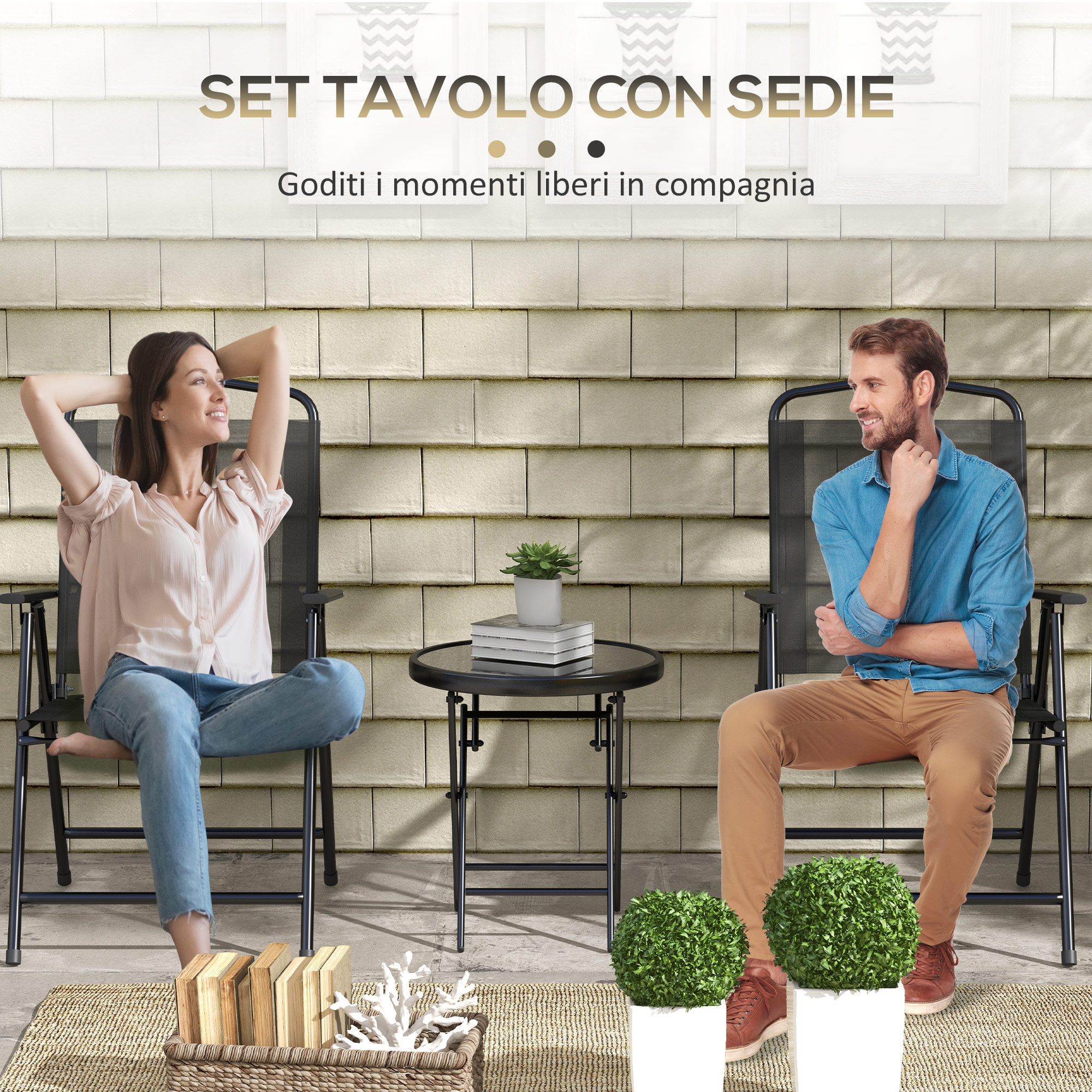 Uomo e donna siedono su sedie accanto a un tavolo. Due cespugli verdi.