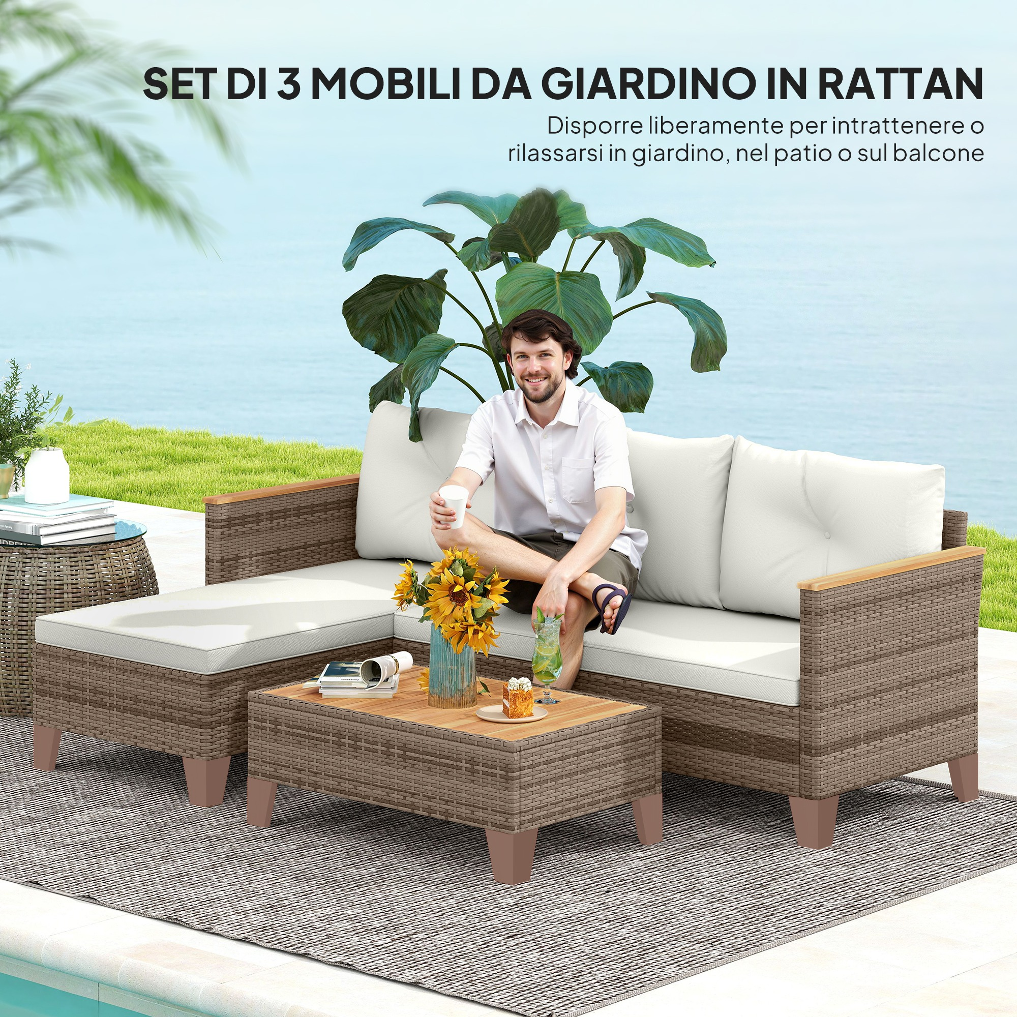 Un uomo siede su un divano in rattan con cuscini bianchi, vicino a un tavolino con fiori.