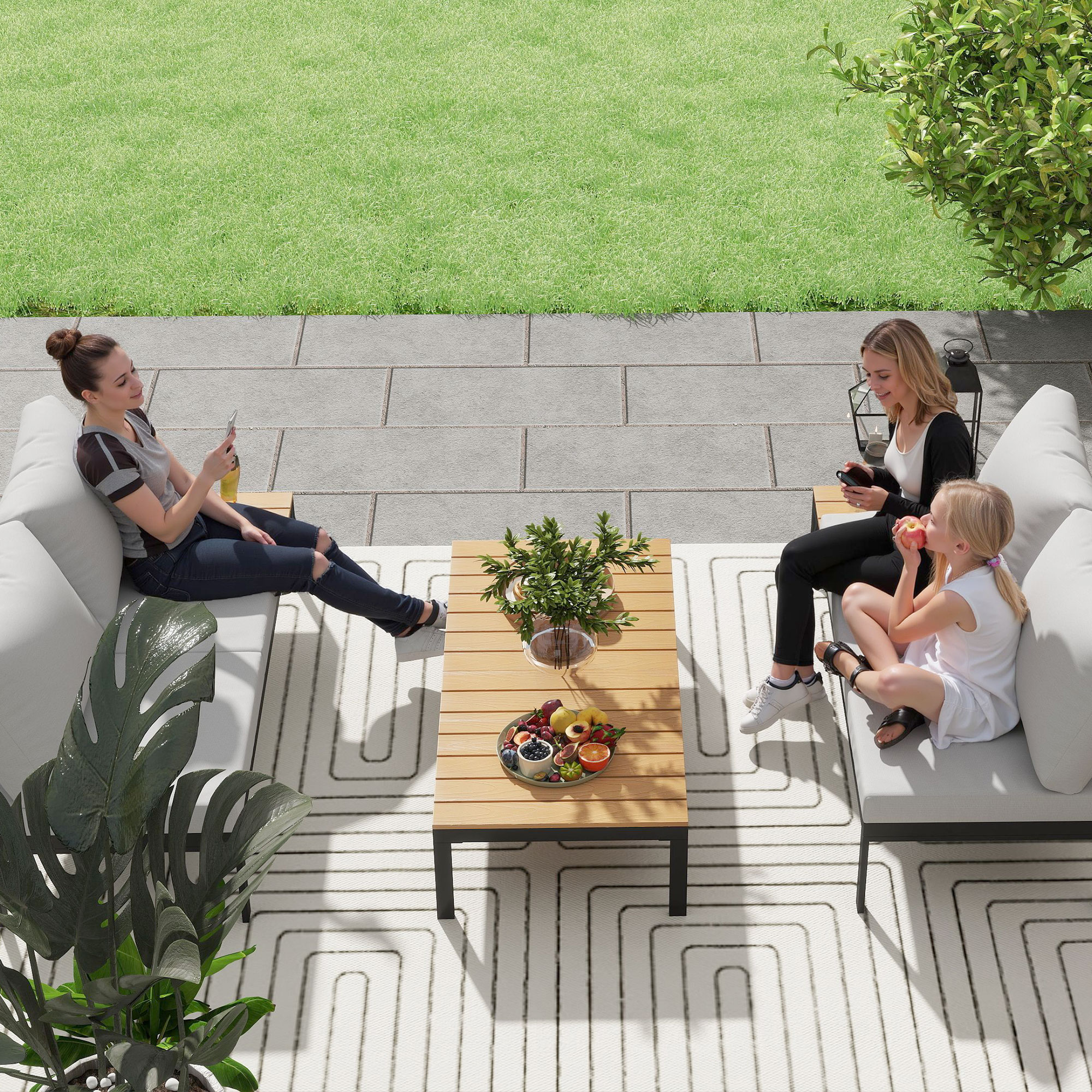 Tre persone si rilassano su un patio con erba e alberi.