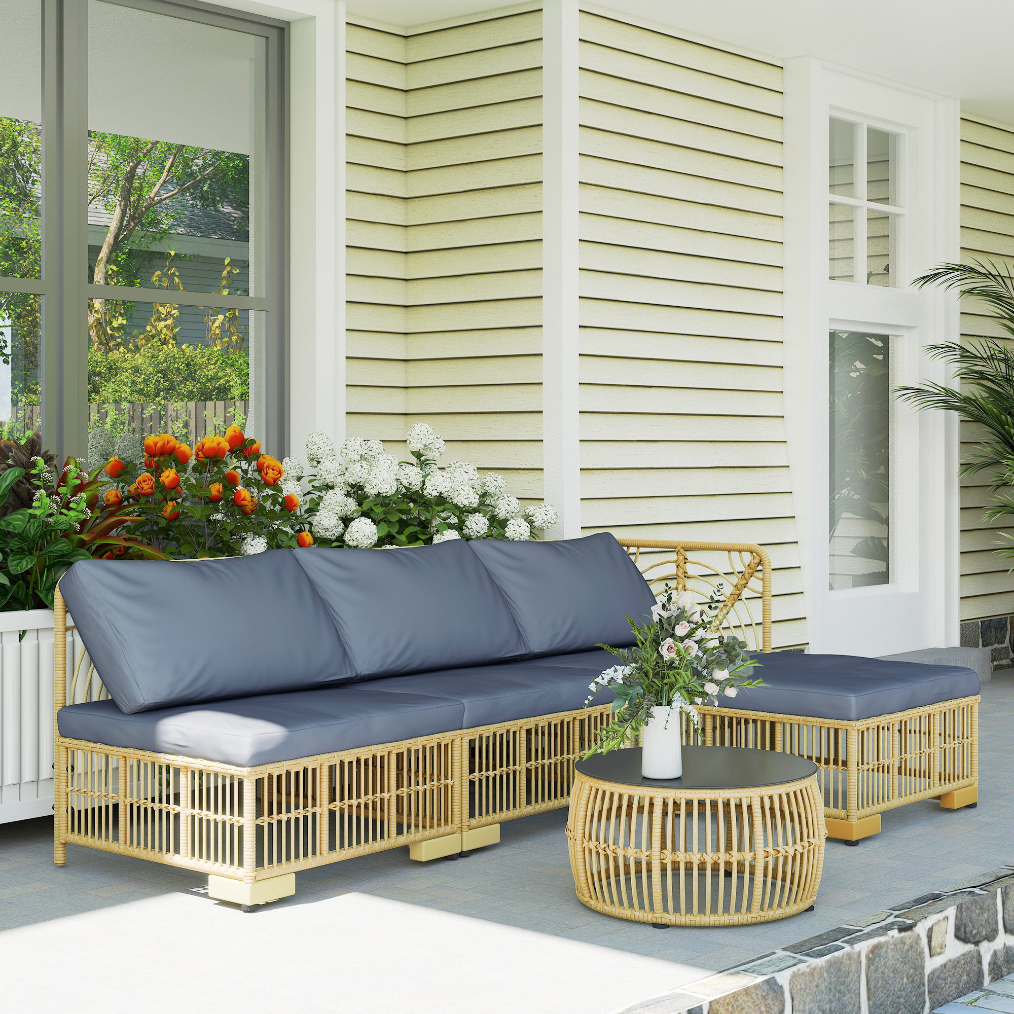 Salotto in rattan con cuscini grigi e fiori su un portico.