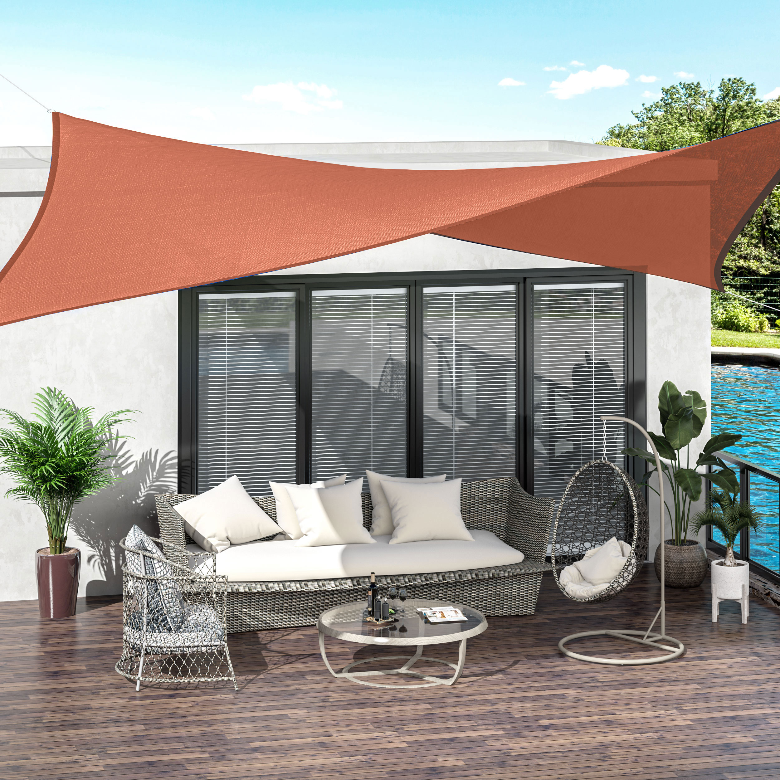 Un patio con mobili da salotto, piante e vela parasole.