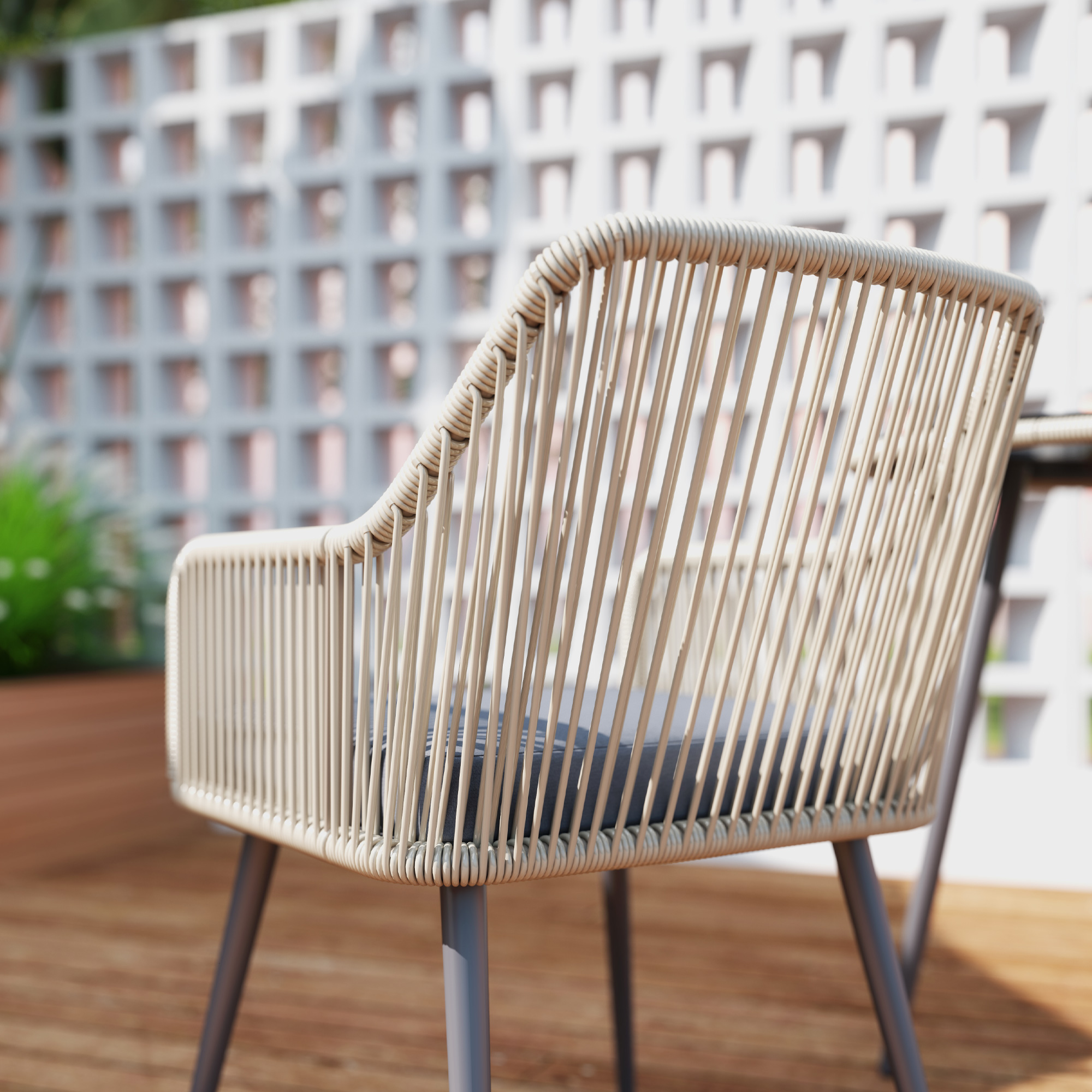Sedia in vimini marrone chiaro con cuscino scuro su terrazzo in legno.