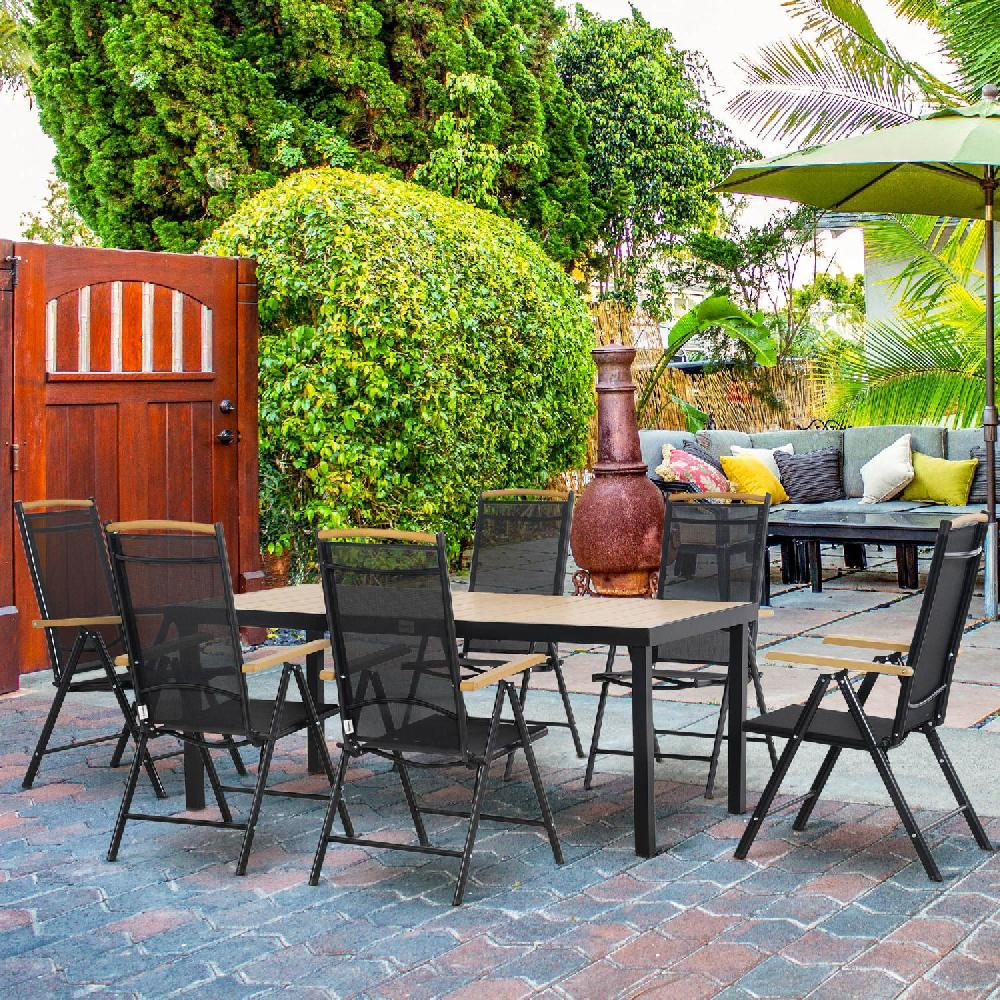 Set da pranzo da esterno con tavolo, sedie, divano e ombrellone su patio pavimentato.
