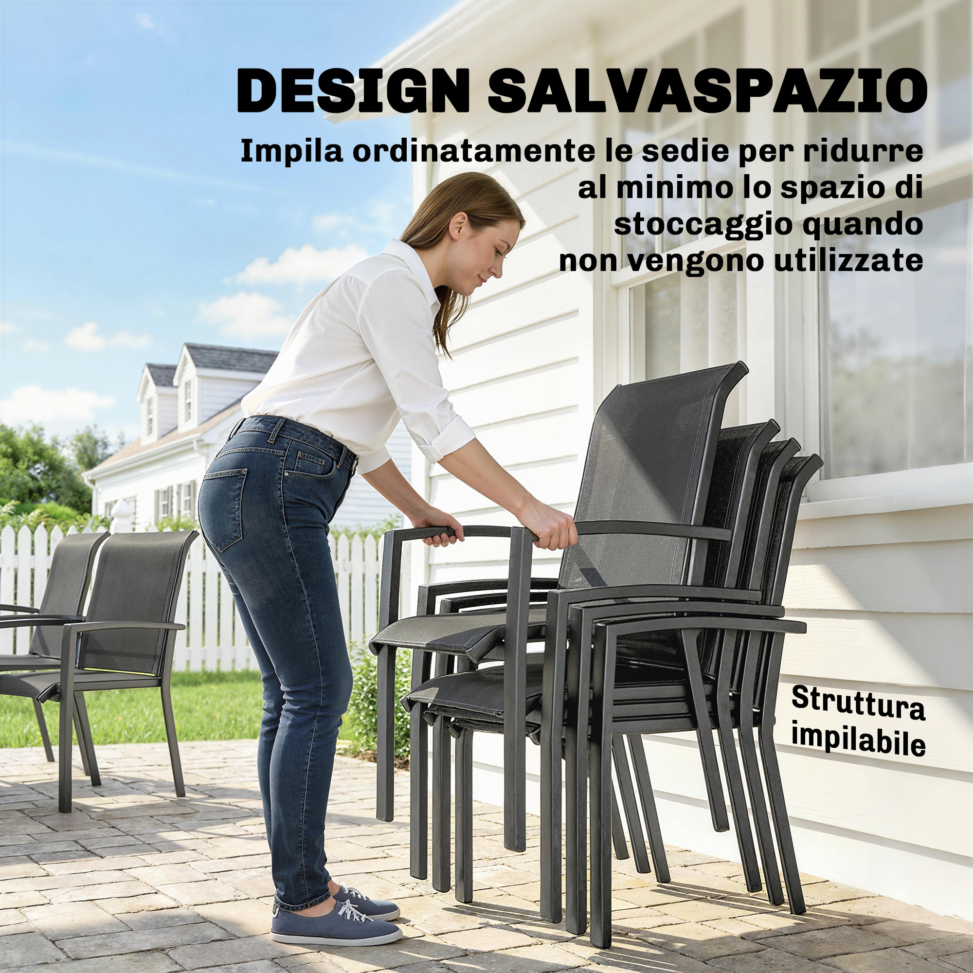 Una donna impila sedie grigie su un patio davanti a una casa bianca.