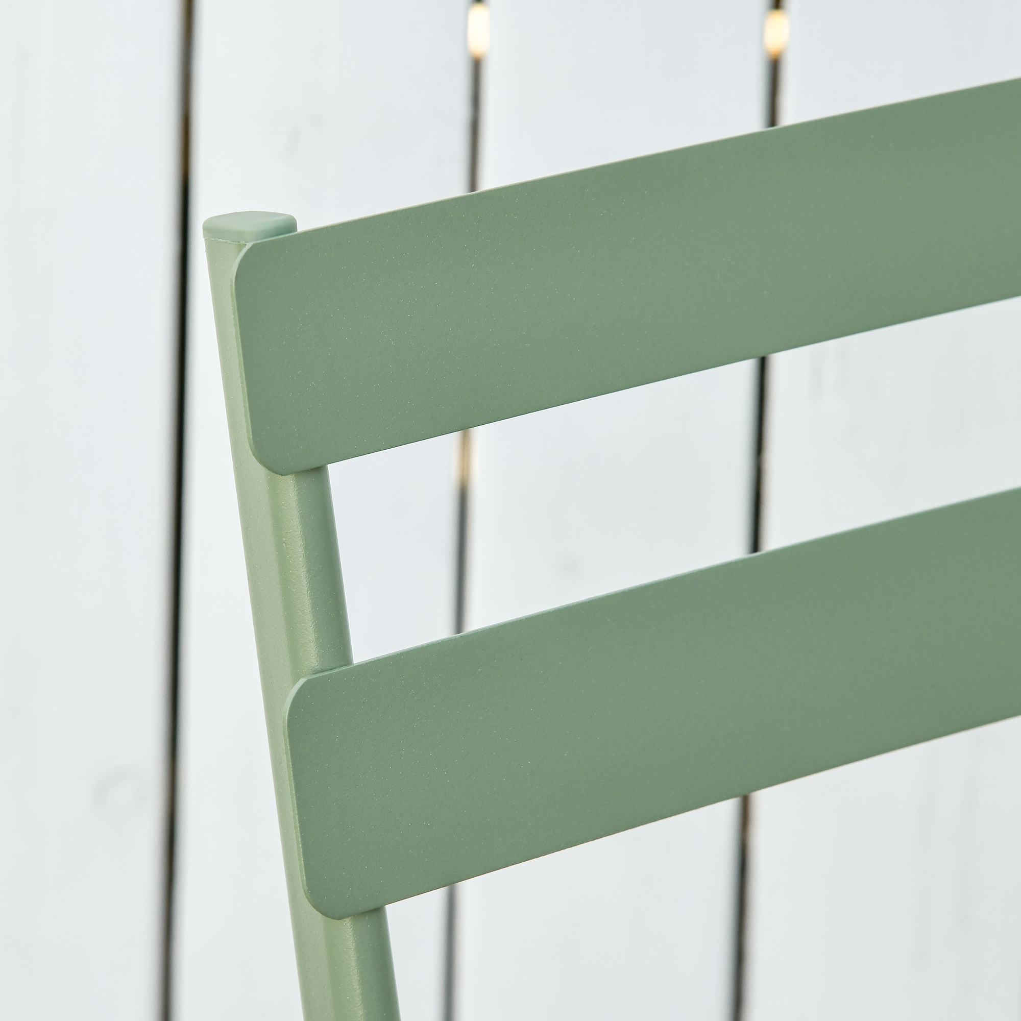 Sedia verde con schienale a doghe su sfondo bianco.