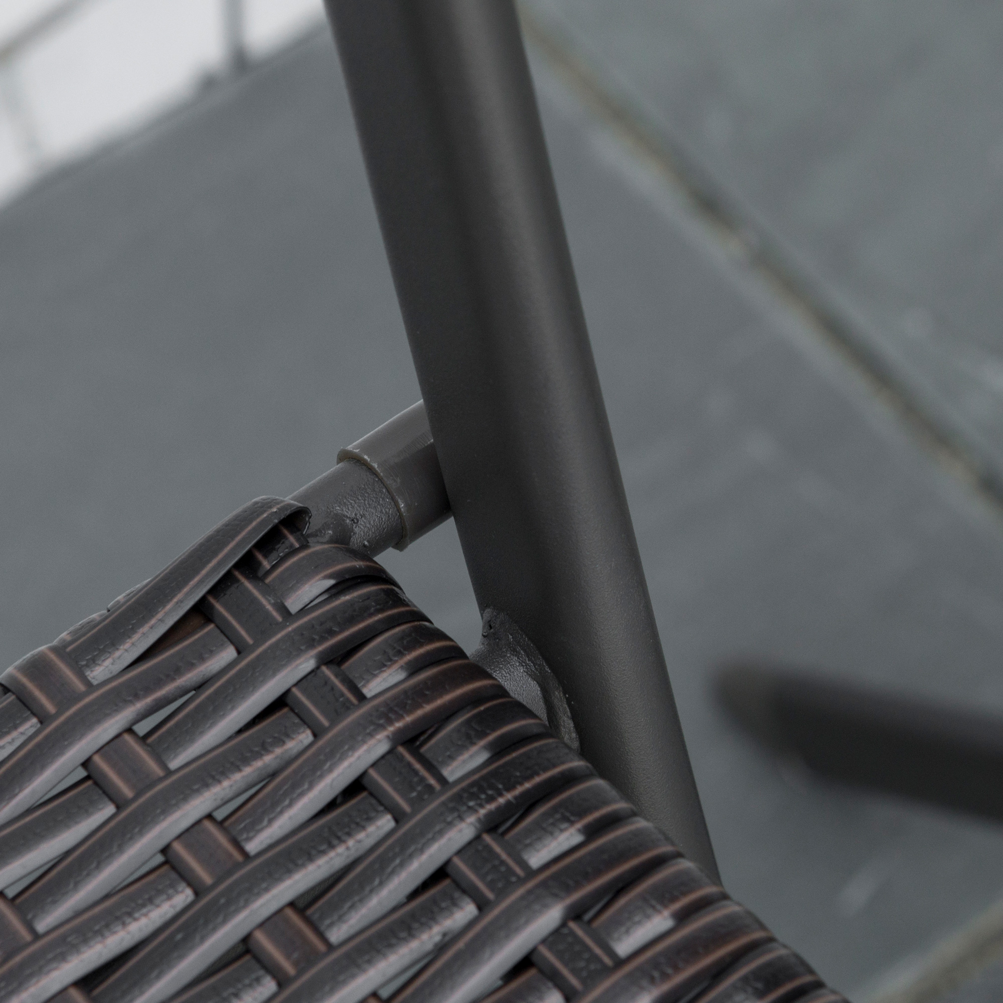 Seduta in rattan marrone con telaio in metallo scuro e piastrelle grigie.