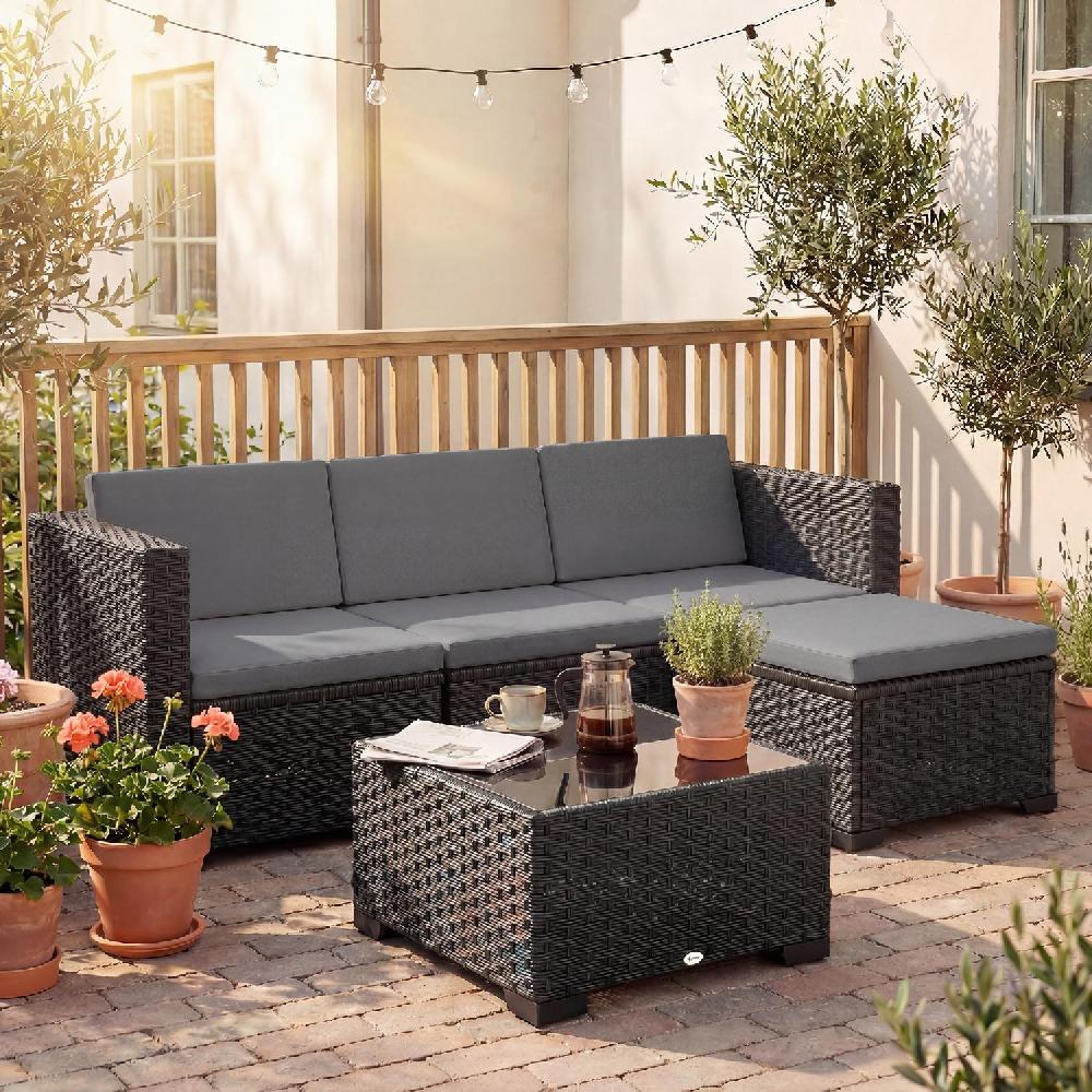 Divano e pouf in rattan scuro con cuscini grigi su un patio in mattoni.