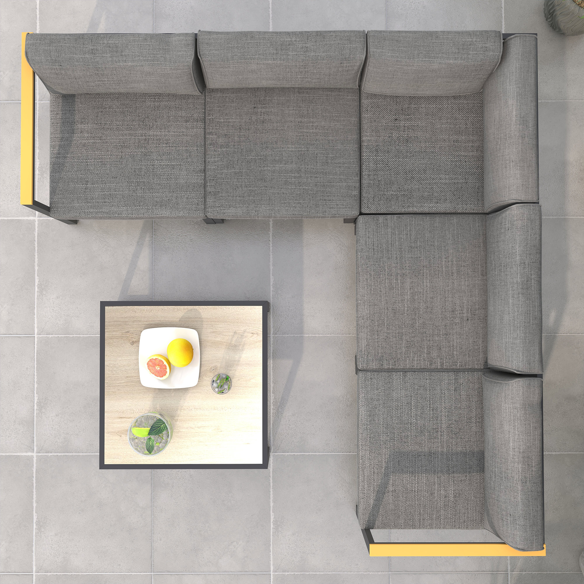 Divano angolare grigio con accenti gialli accanto a un tavolo in legno con frutta e bevande.