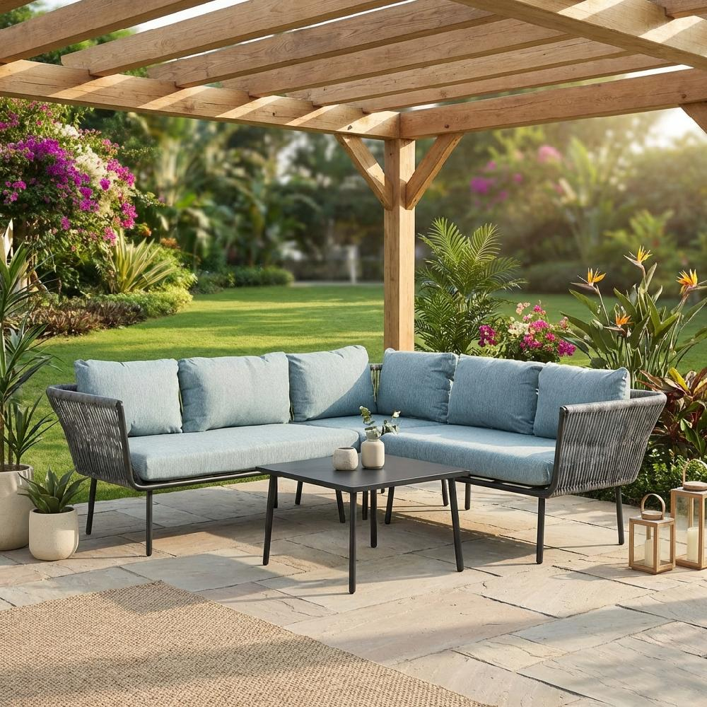 Divano angolare blu chiaro sotto pergola in legno con tavolino, circondato da piante.